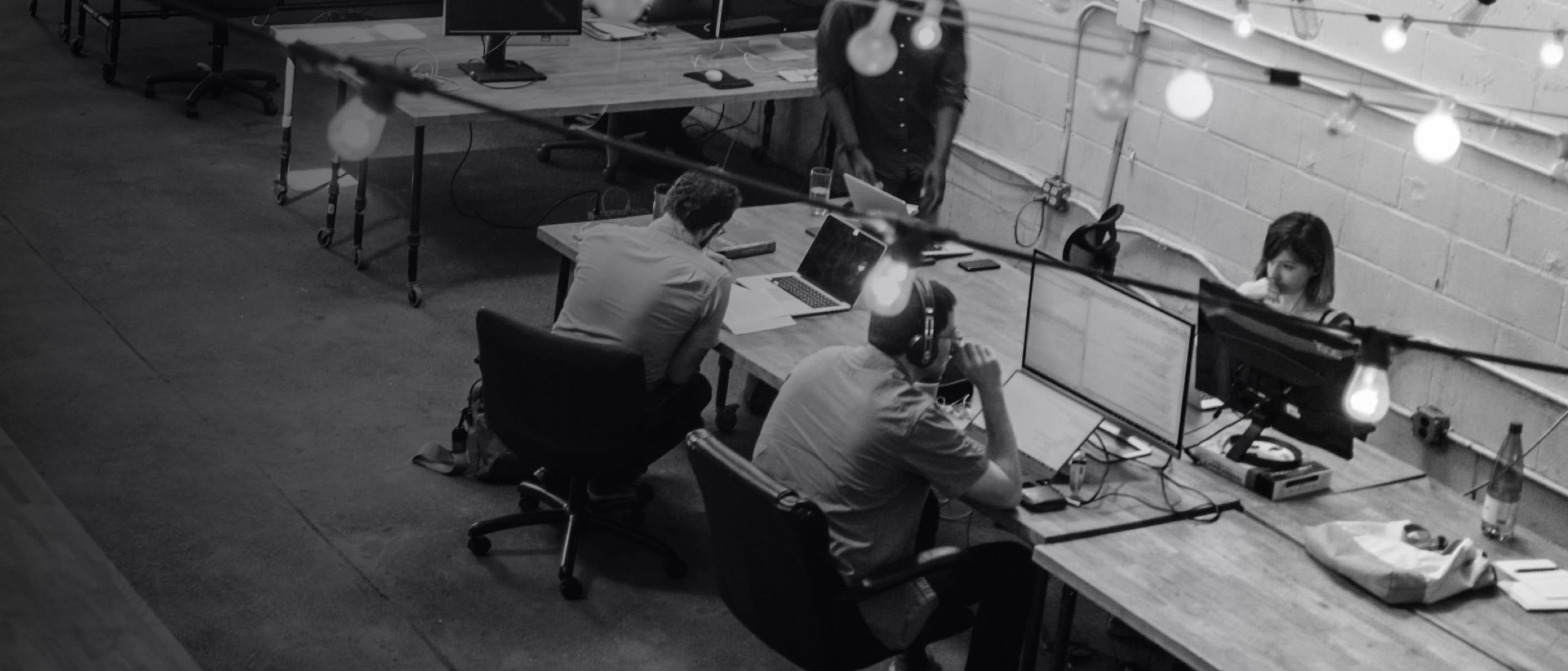 A high-angle photo of a team working at desks with computers and a caption saying build an ai-ready workforce fully prepared for human-silicon collaboration