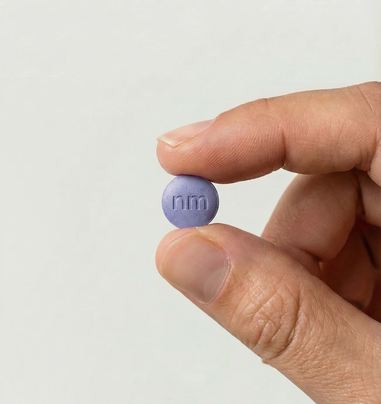 Hand holding a single Compounded Tirzepatide tablet