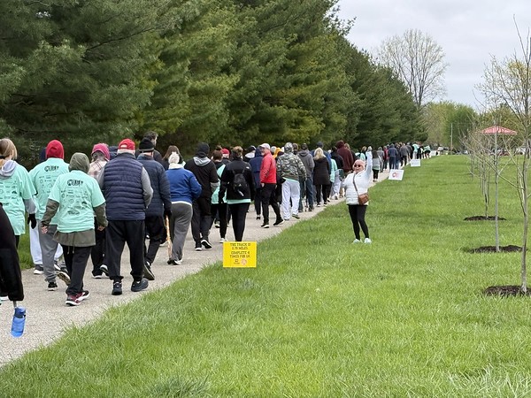 A woman in a red top sits at a desk, talking to someone out of view in an office setting.