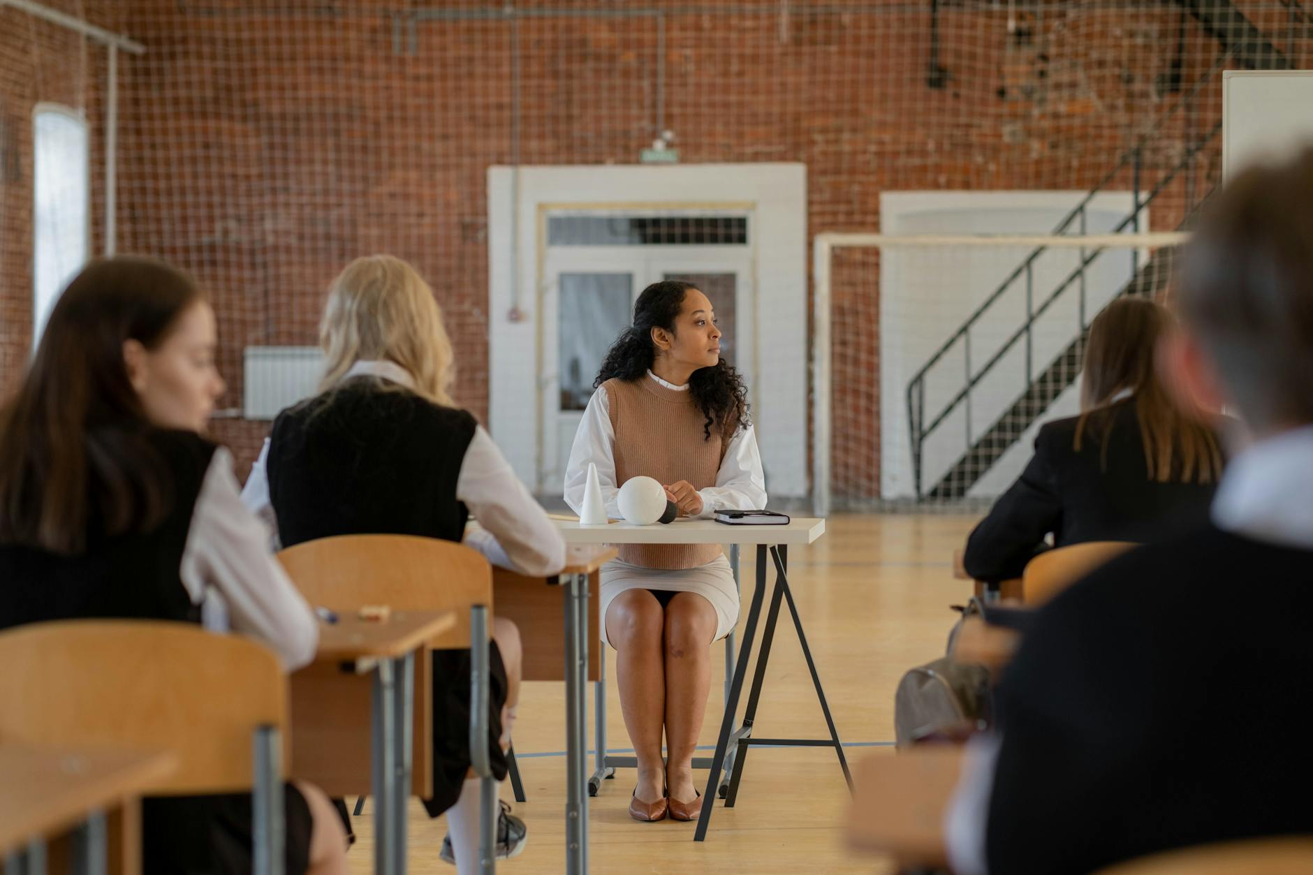 Middle school students working in small groups while a teacher uses a hand signal for classroom management.