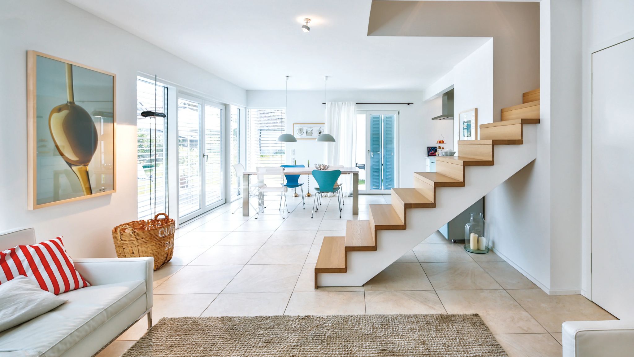 Moderne, helle Wohnküche mit Essbereich, Treppe in Naturholzoptik und großflächiger Glasfront, stilvolle Einrichtung.
