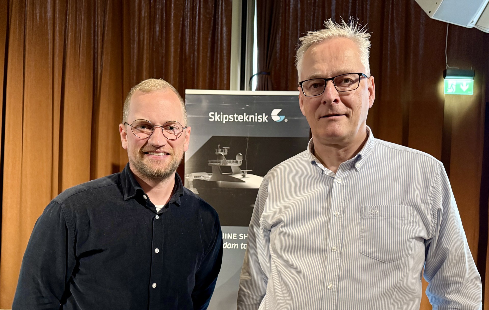 A person wearing a virtual reality headset stands in front of multiple screens, engaged in a digital experience.