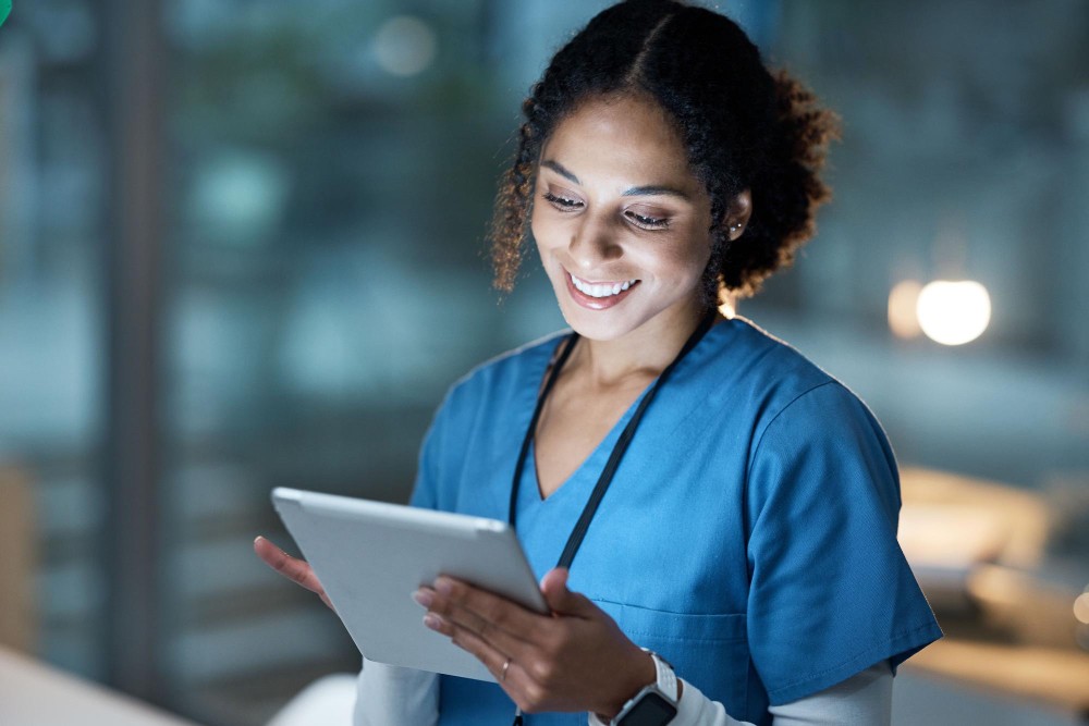 Woman smiling while using a tablet, representing automated detection of anomalies and proactive incident prevention.