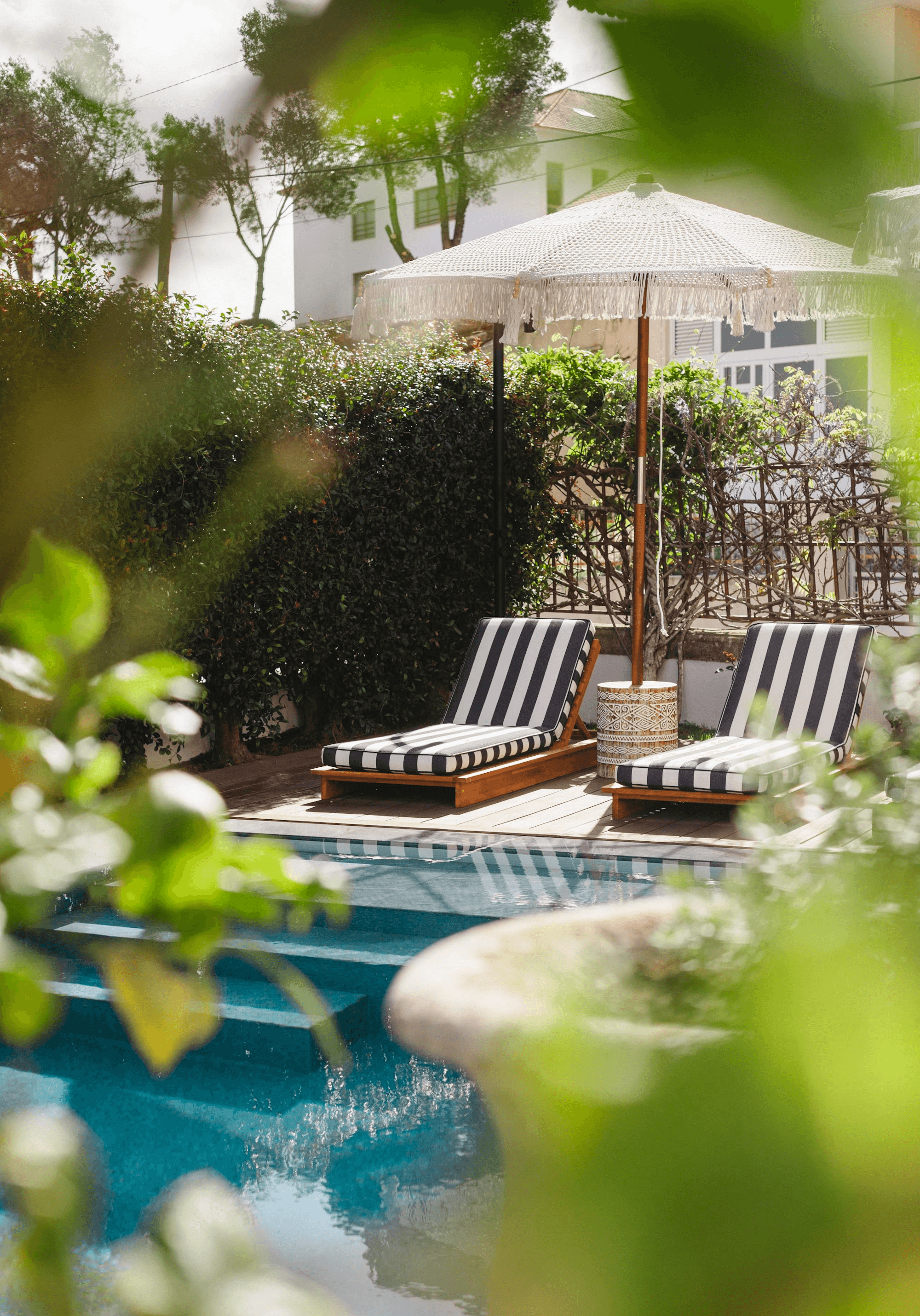 Pool and sunbeds at The Salty Cascais with umbrellas and coastal backdrop.
