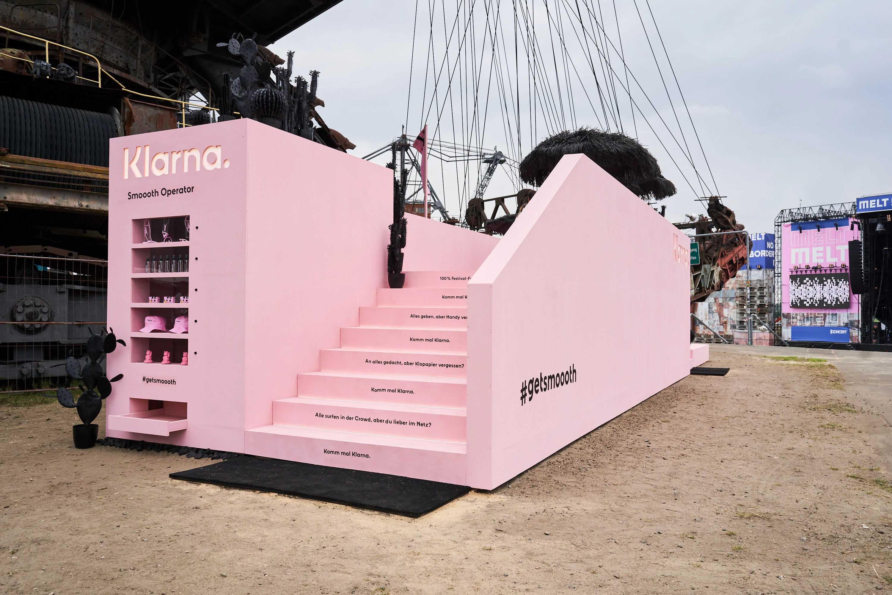 Side view of the pink Klarna Smoooth Operator installation with shelf niche, stairs and #getsmoooth lettering at Melt Festival.