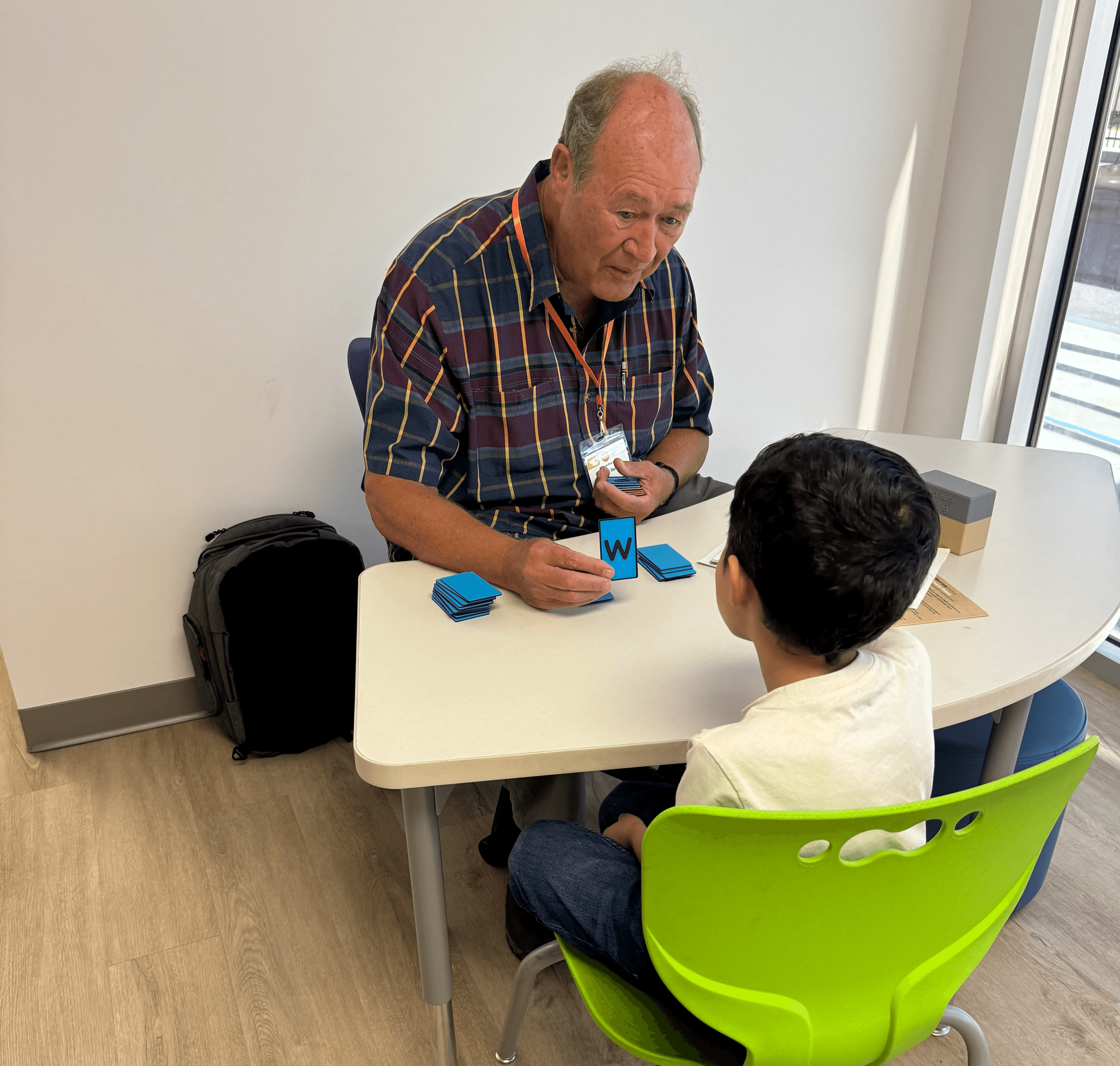 One-on-one early literacy session with a Read With Me volunteer teaching phonics, letter sounds, phonemic awareness, and reading instruction to a child using Word Nuts Reading materials.