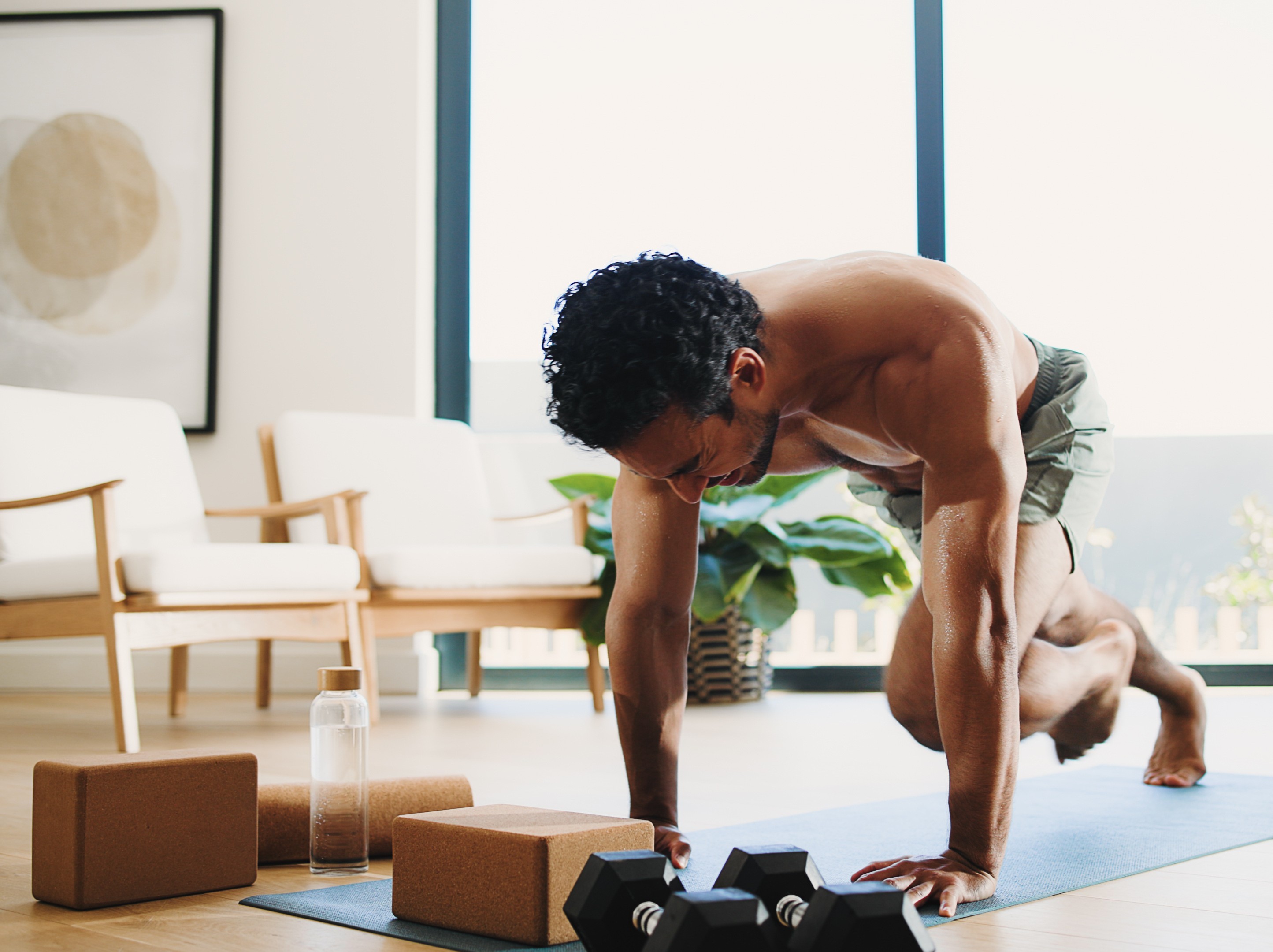 man doing an intense HIIT at-home workout to lose weight in a sunny room with a beautiful view