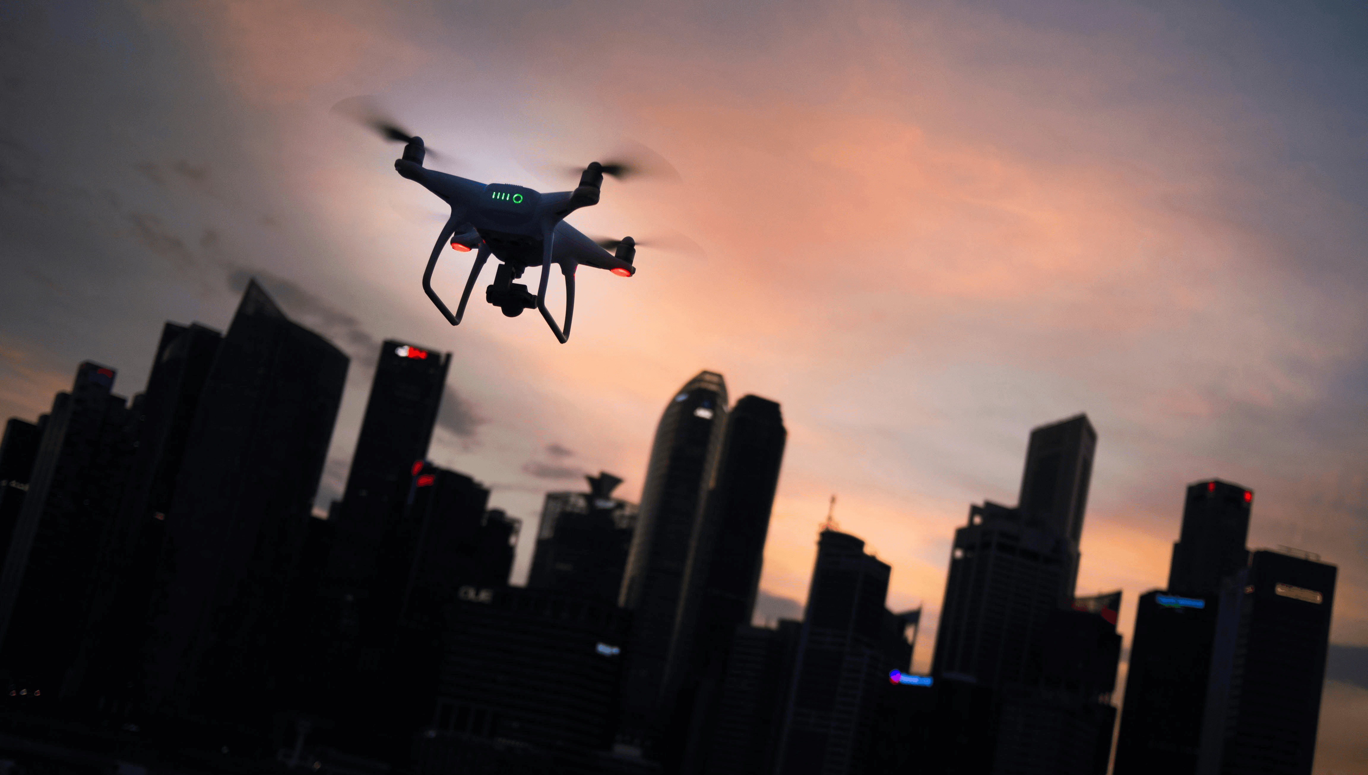 silhouette of quadcopter drone hovering near the city