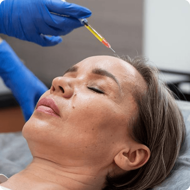 Close-up view of a woman undergoing a biocellular medicine treatment, with a focus on her face as she receives an injection. She has a calm and positive expression, indicating her comfort with the procedure. The clinical setting is clean and professional, emphasizing the advanced technology and care involved in biocellular therapies aimed at enhancing health and wellness.