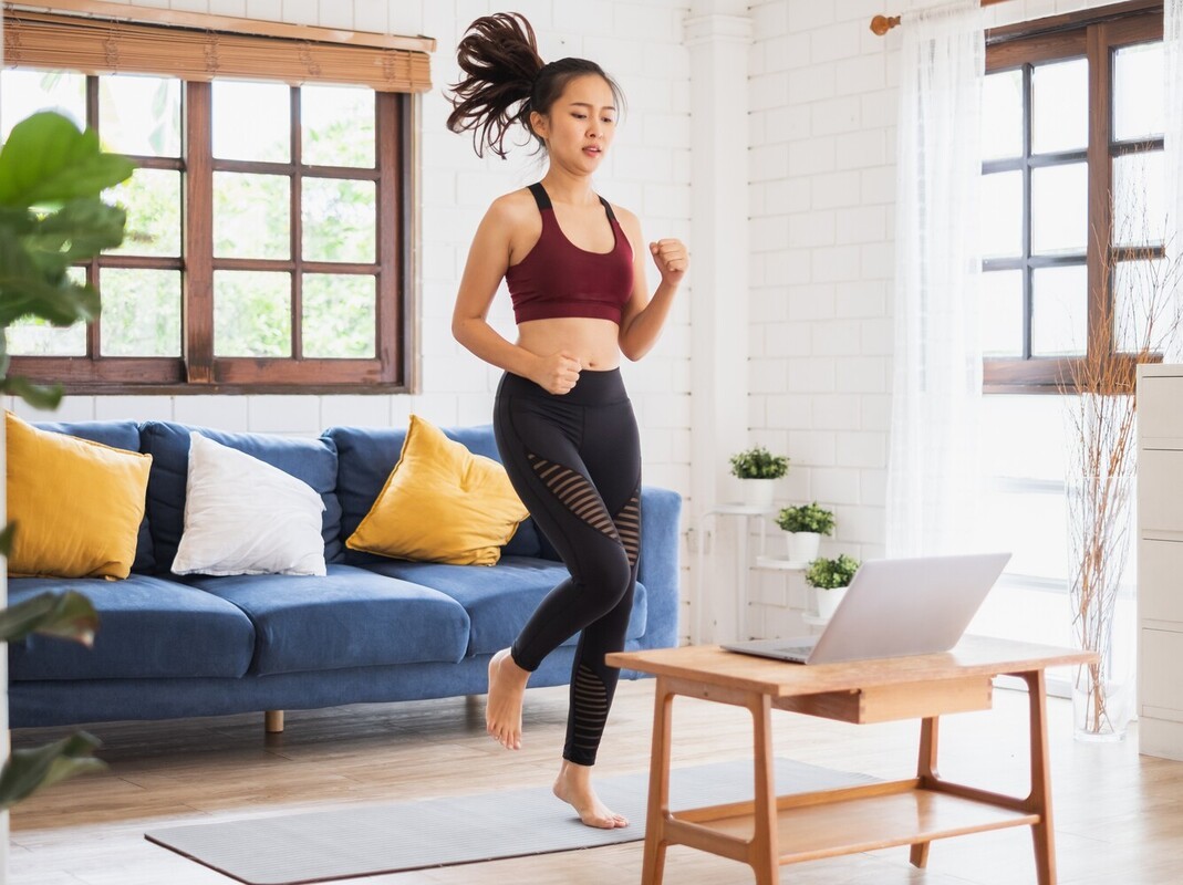 woman doing cardio in her living room to warm up for her weight loss workout at home