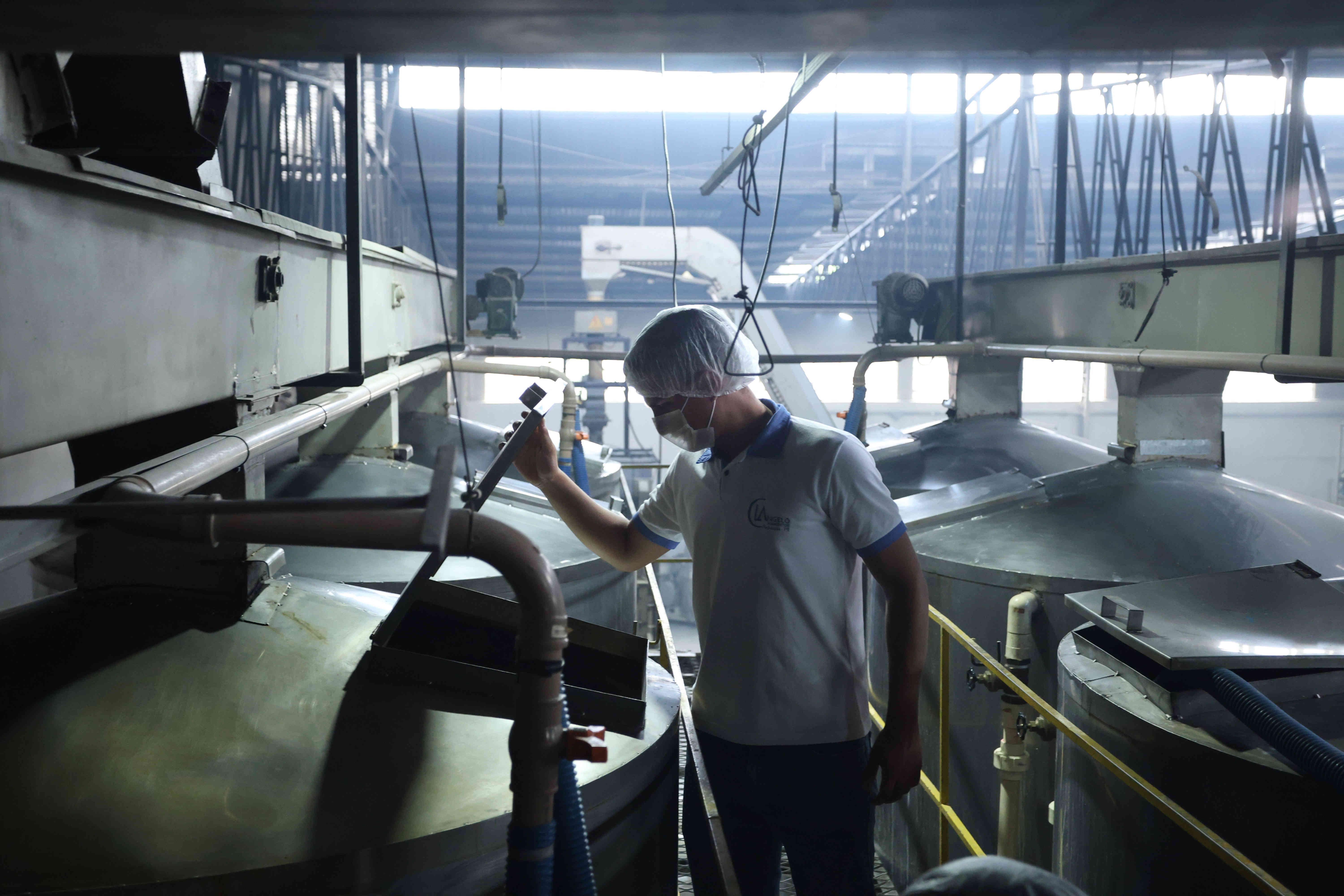 Funcionário da CL Angelo com EPI operando equipamento de moagem em ambiente industrial