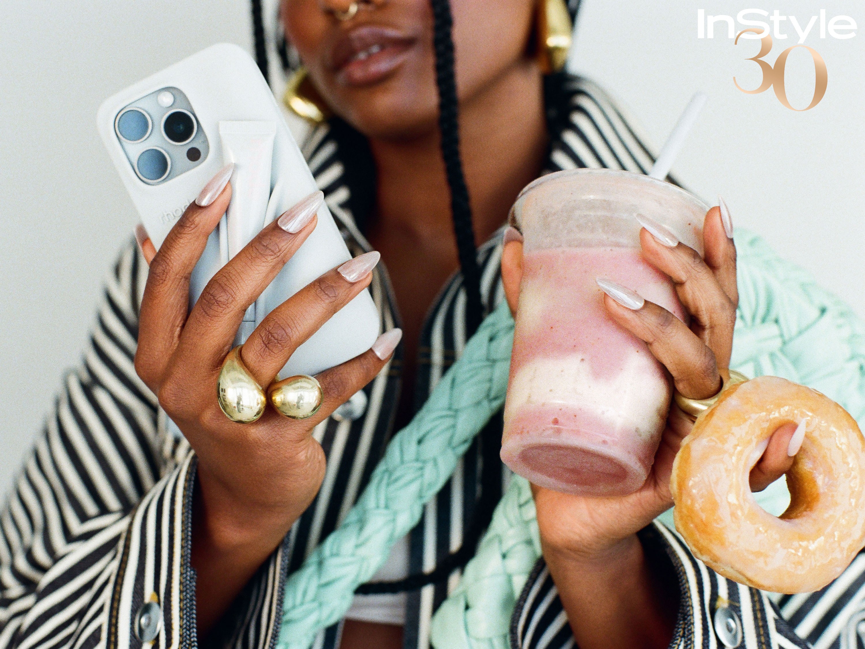 Glazed chrome manicure holding a phone beside a smoothie and glazed donut