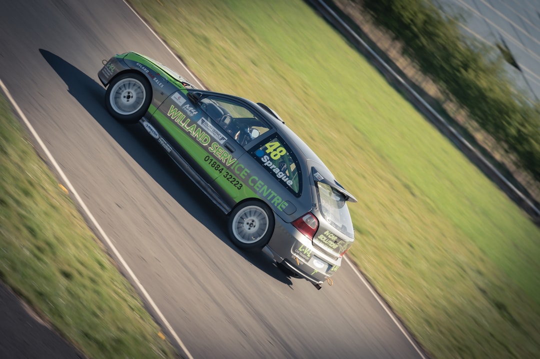 Race car speeds down a track with green grass.