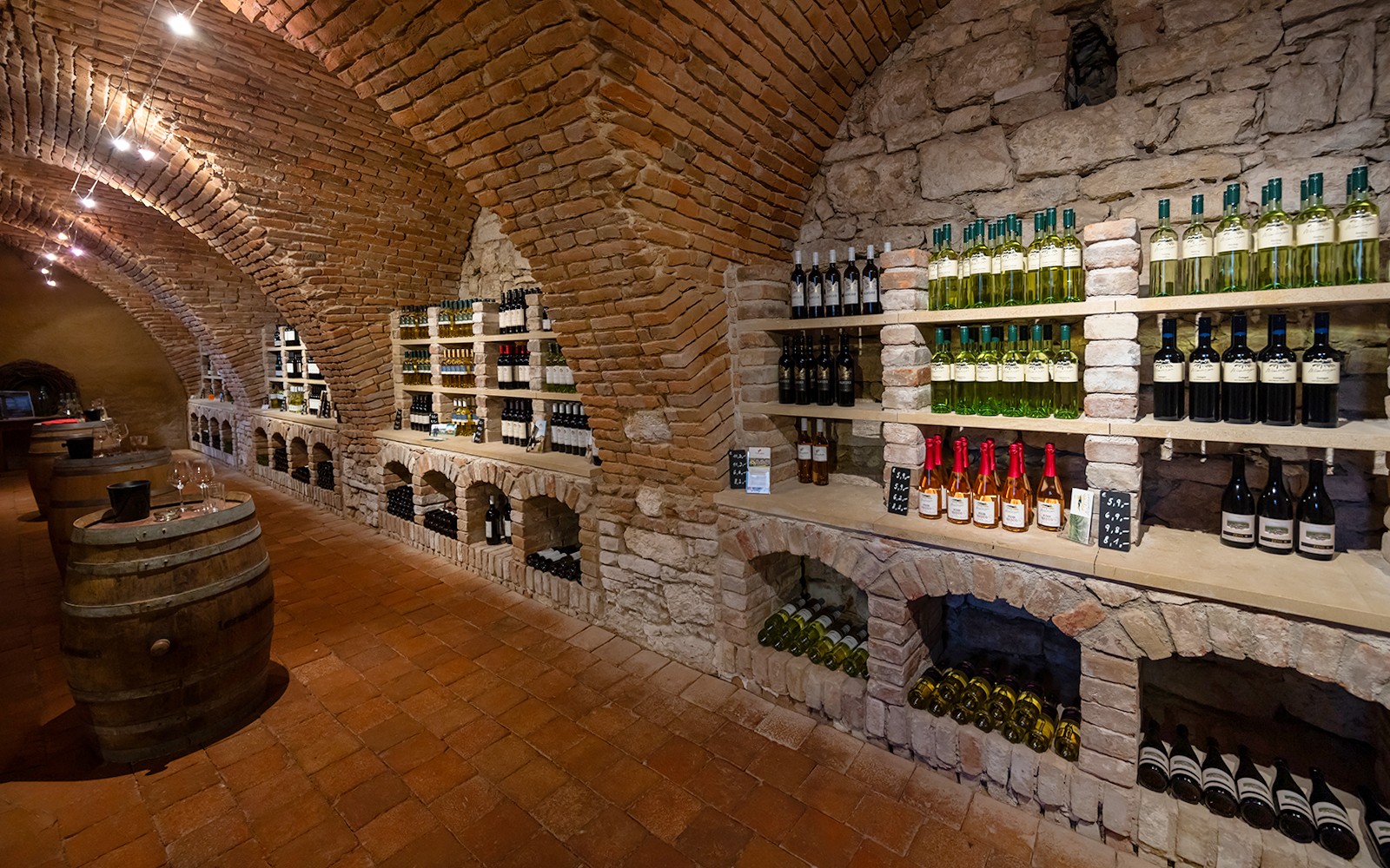 Privater Weinkeller mit Flaschen auf Regalen und Holzfässern für geführte Weinverkostungen.