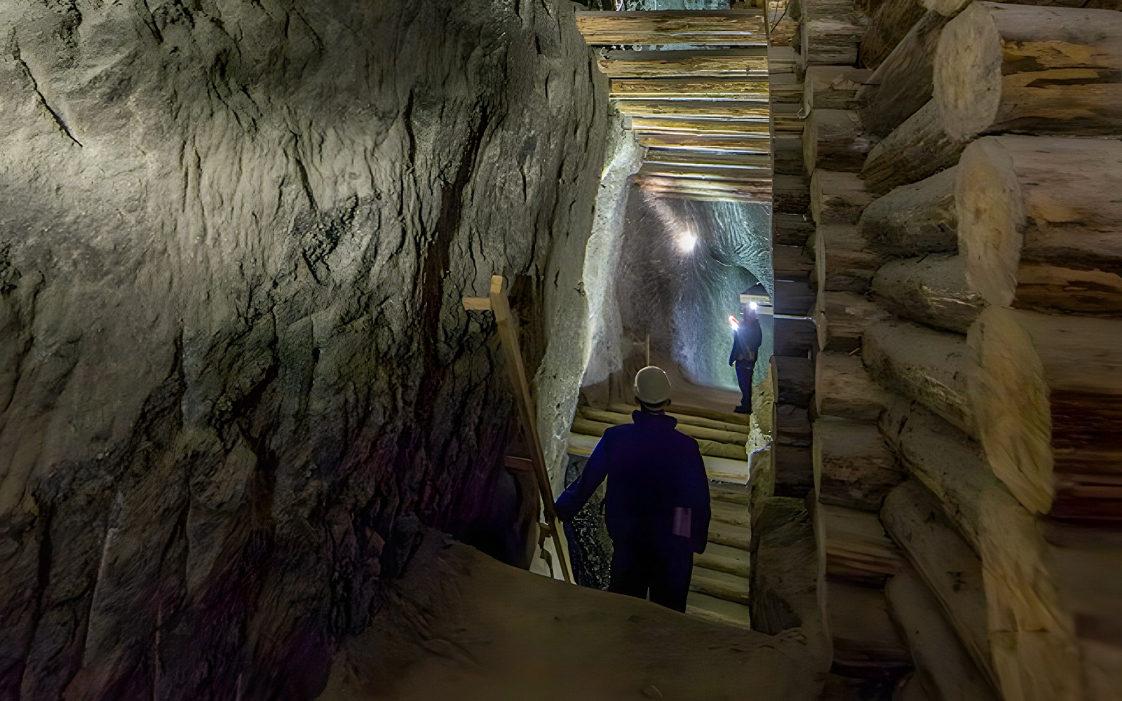 Visitors exploring Bochnia Salt Mine tunnel with wooden supports.