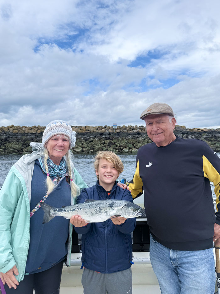 Family displaying fresh salmon on Seattle Puget Sound fishing trip.