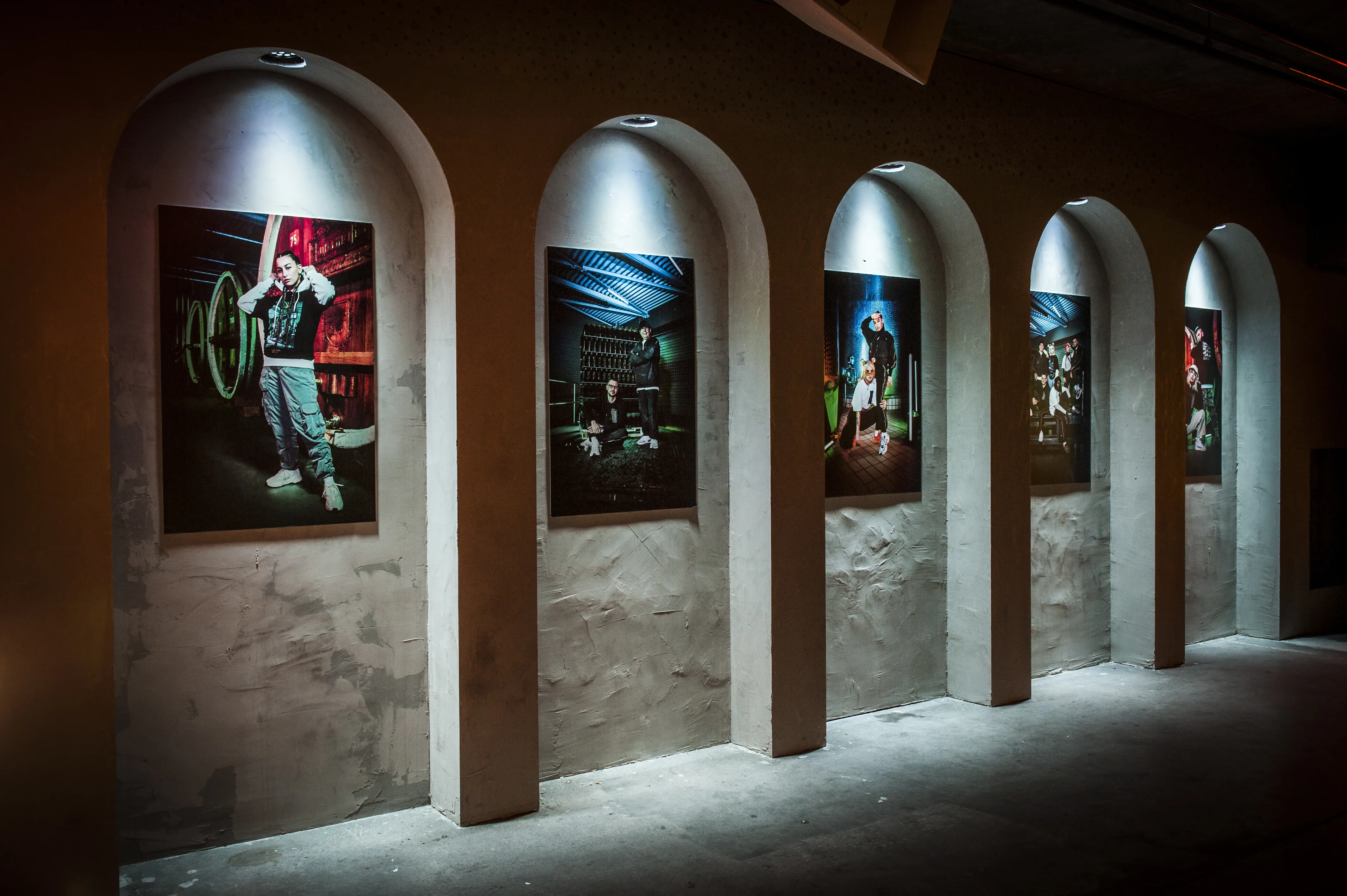 Arched concrete niches with spotlit streetwear portrait photographs at the JÄGERMEISTER streetwear launch.