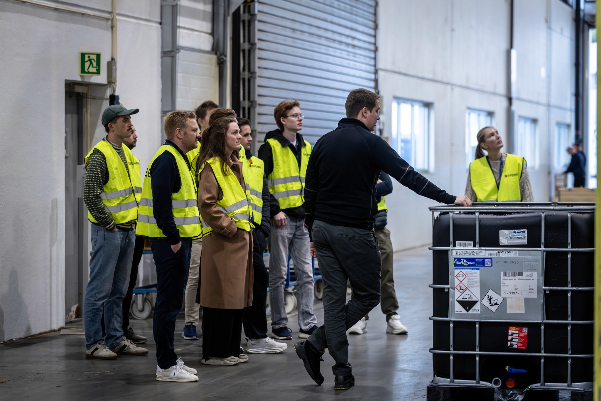 A group of people mingling at an event, with one man looking upwards, appearing deep in thought.