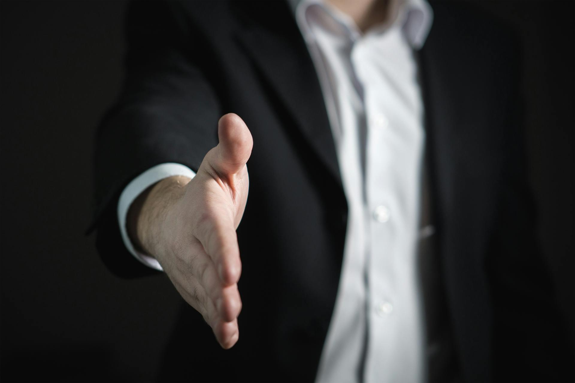 Person standing with hand reached out to greet