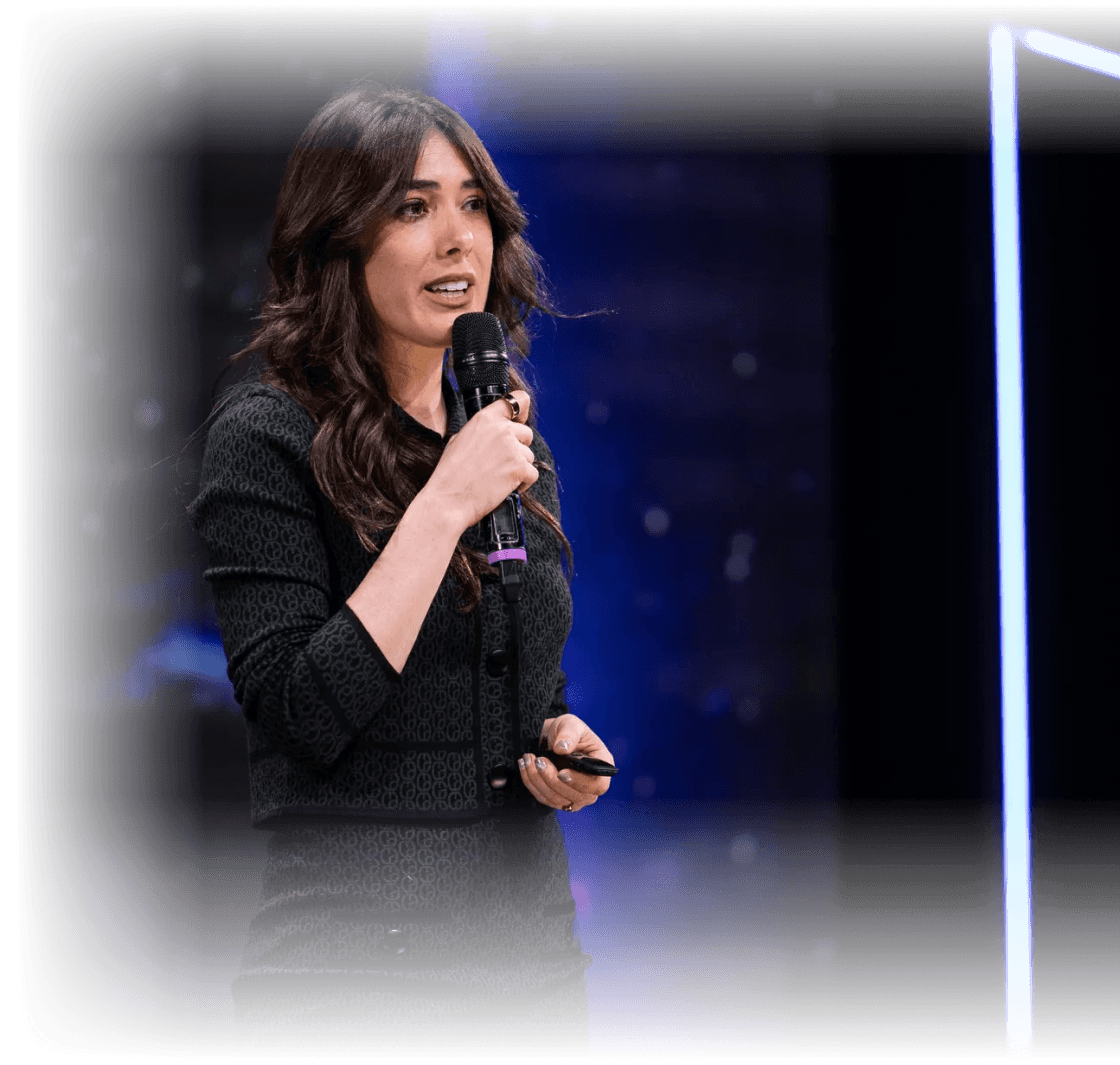 Caroline Mignaux lors d’une conférence, tenant un micro, en train de présenter sur scène