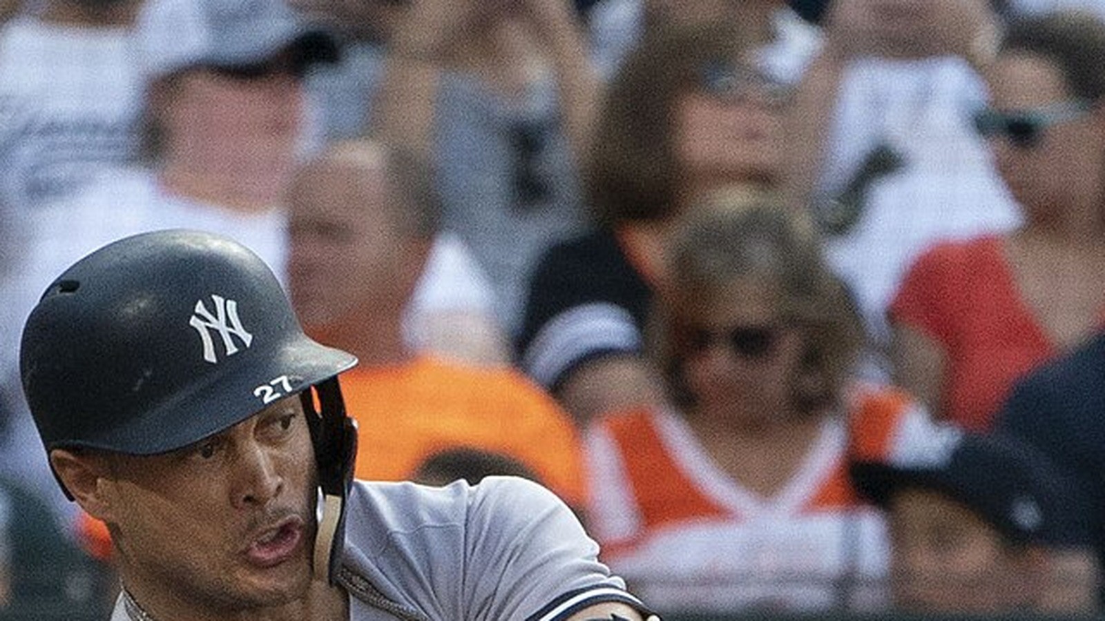 Giancarlo Stanton in a Yankees grey jersey mid-swing, face centered
