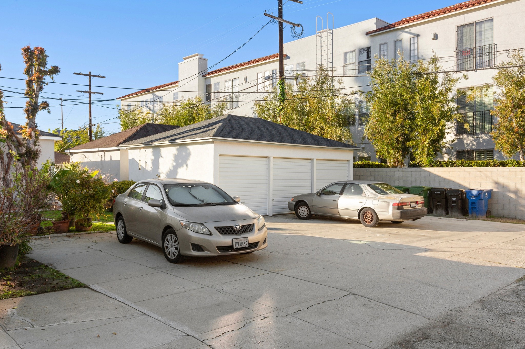 Rear exterior view highlighting parking access and neighboring properties behind the triplex at 10651 Whipple.