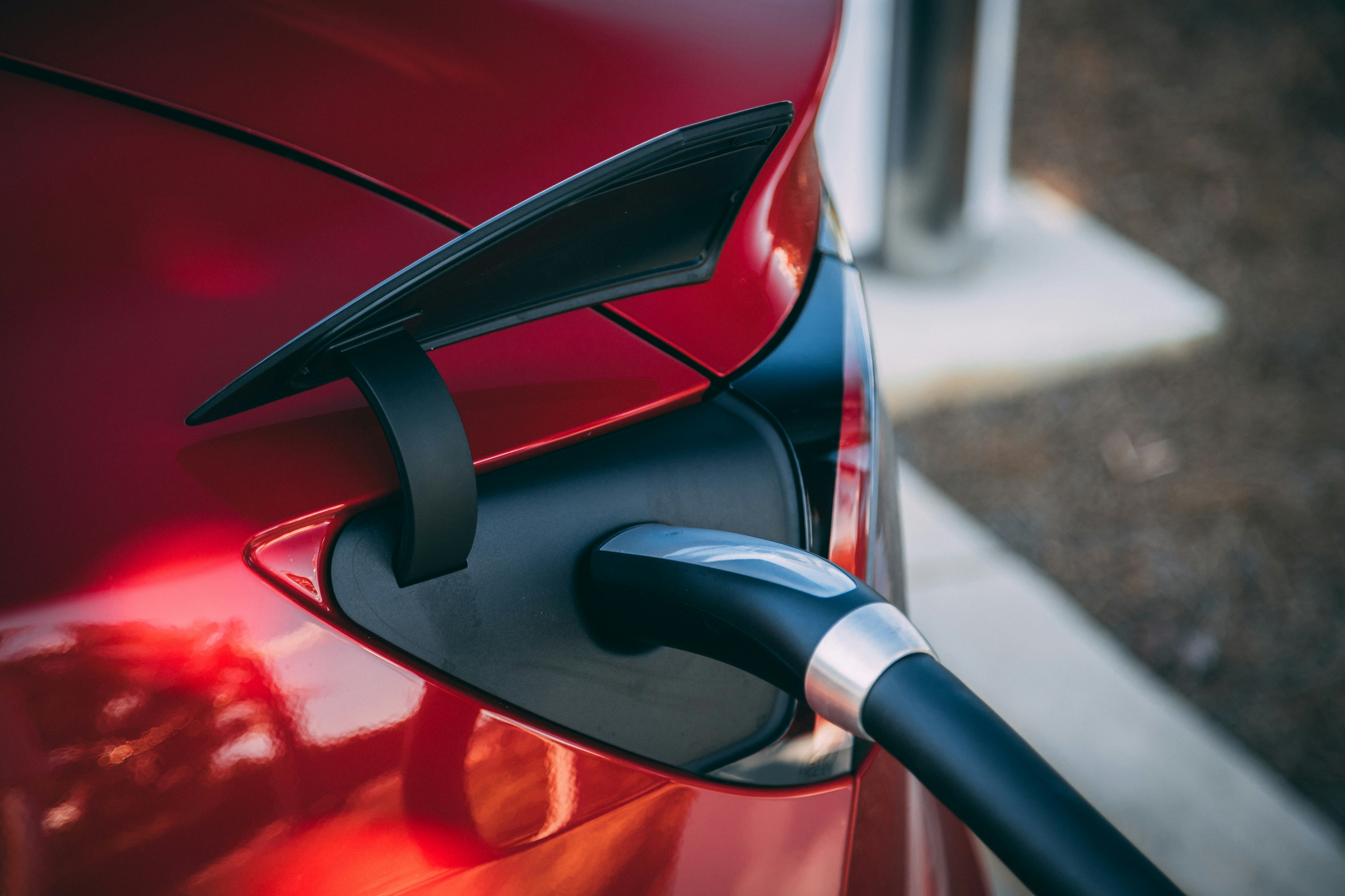 An electric car plugged in at a roadside charger in the evening