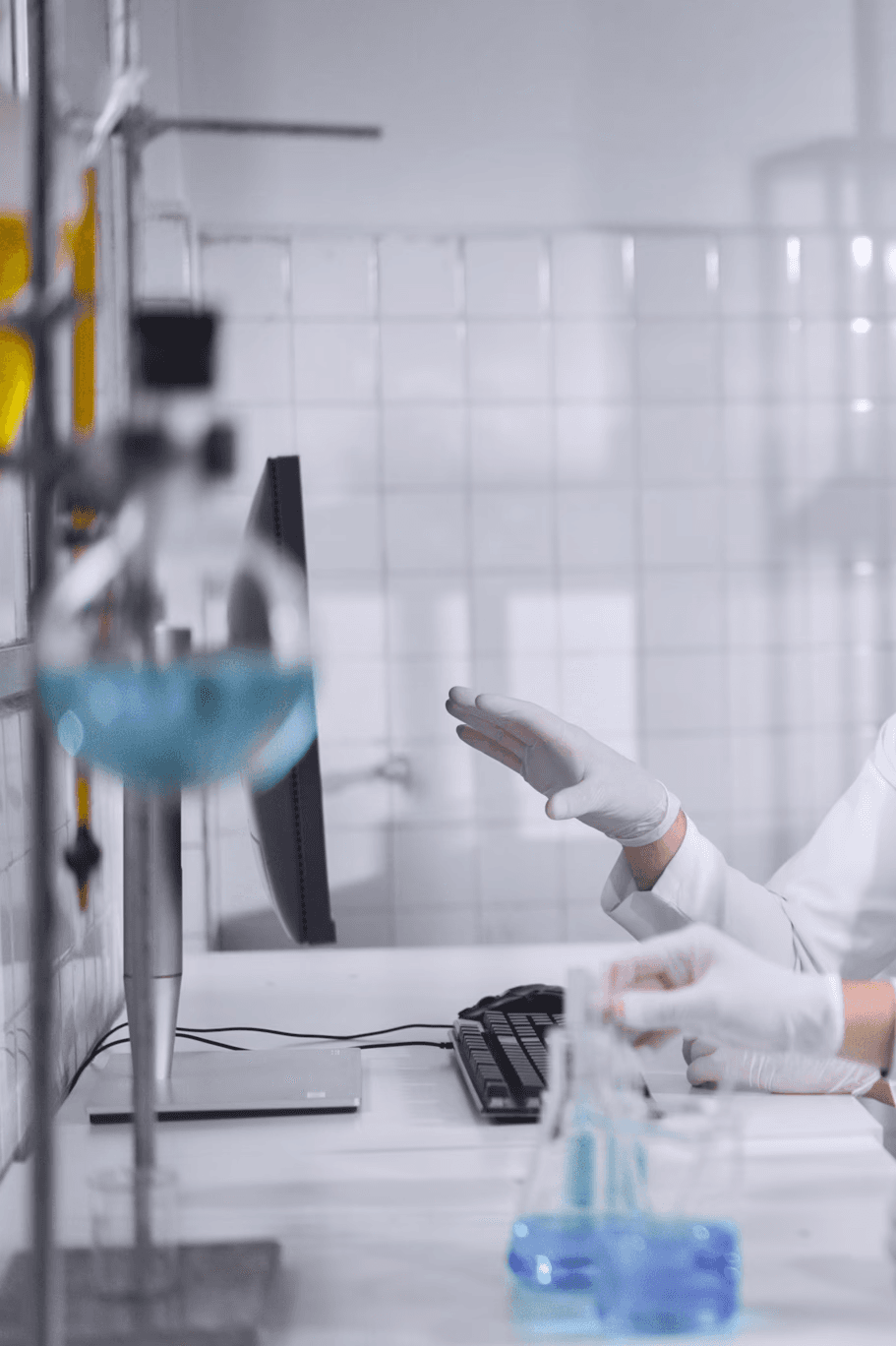Close-up portrait of a person wearing a gray insulated hooded jacket with the hood up, showing their face framed by the hood against a light background.