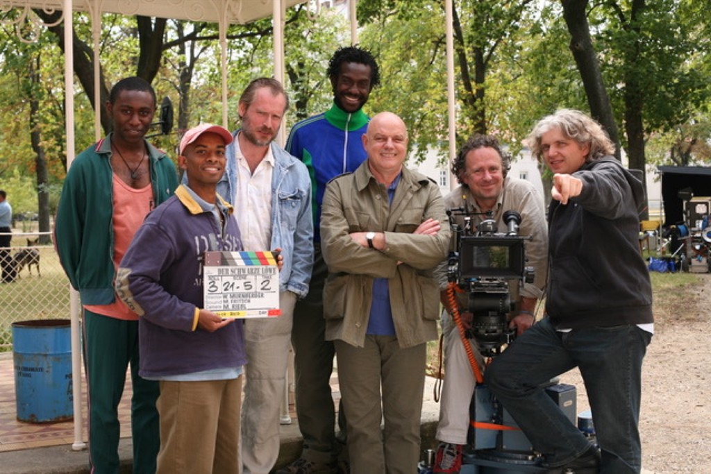 Hosh with colleagues beside a film camera and clapperboard