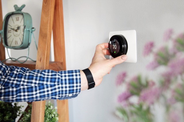 Hand adjusting thermostat after hvac maintenance service.