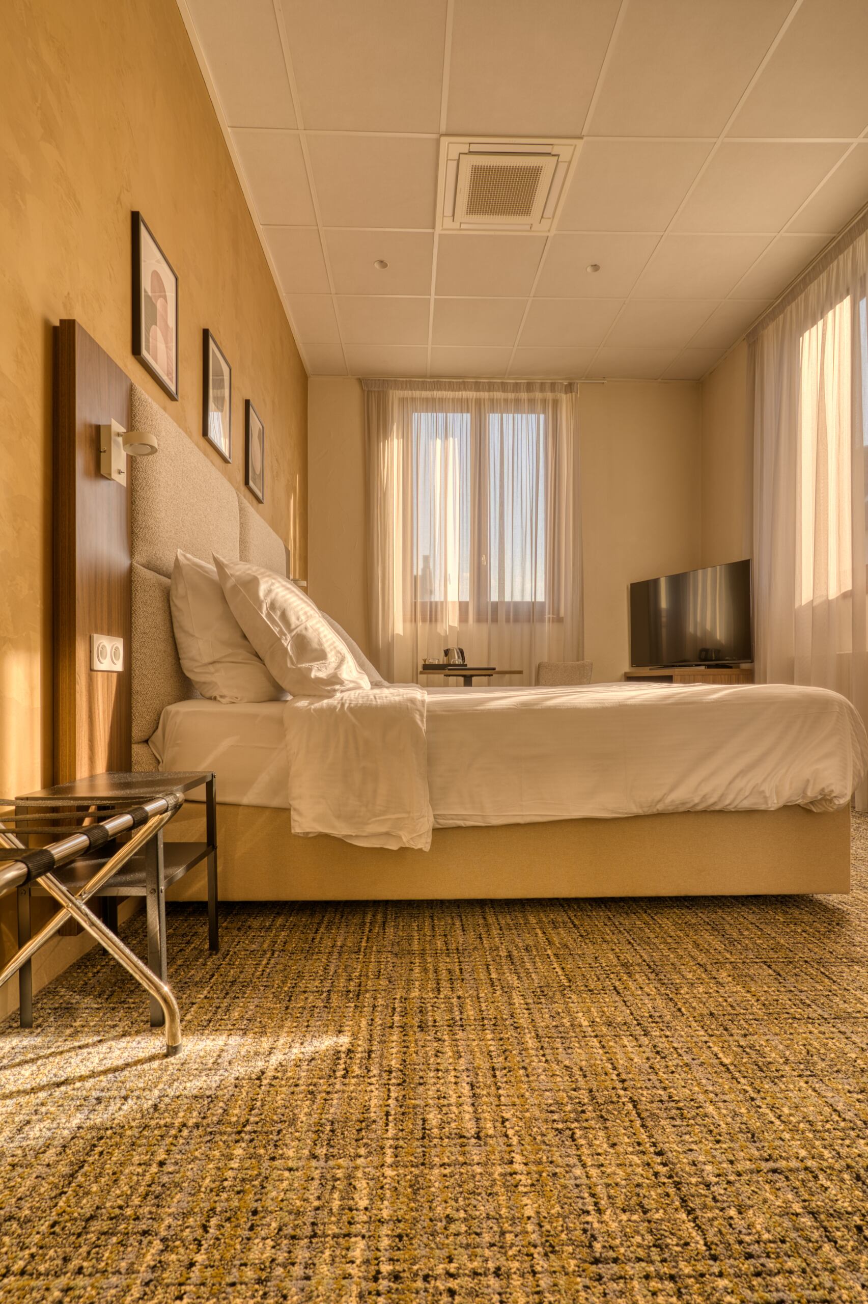 Photographie immobilière professionnelle d'une chambre haut de gamme : lit Queen Size avec literie premium, éclairage tamisé et décoration moderne dans un appartement de standing.