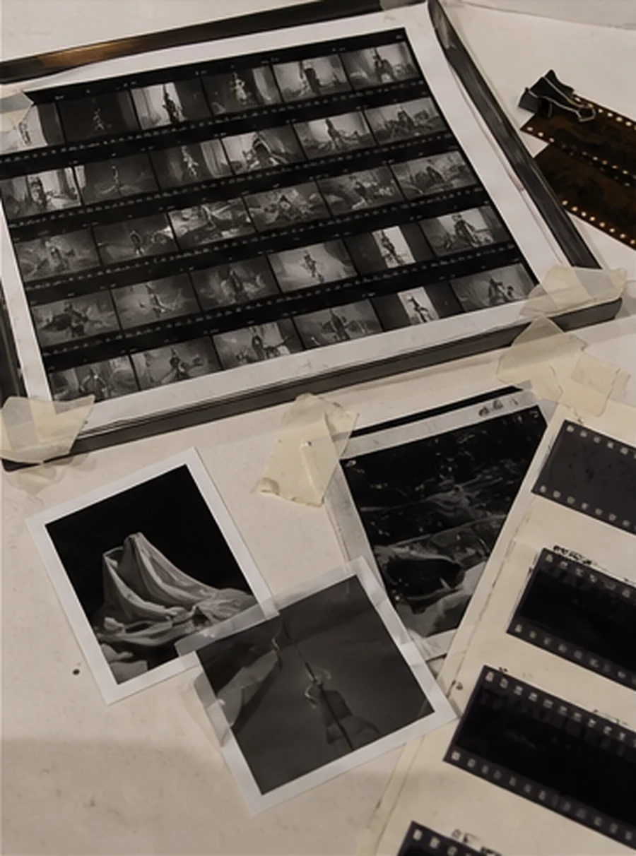 Film strips, taped proof prints and contact sheets spread across a studio desk.