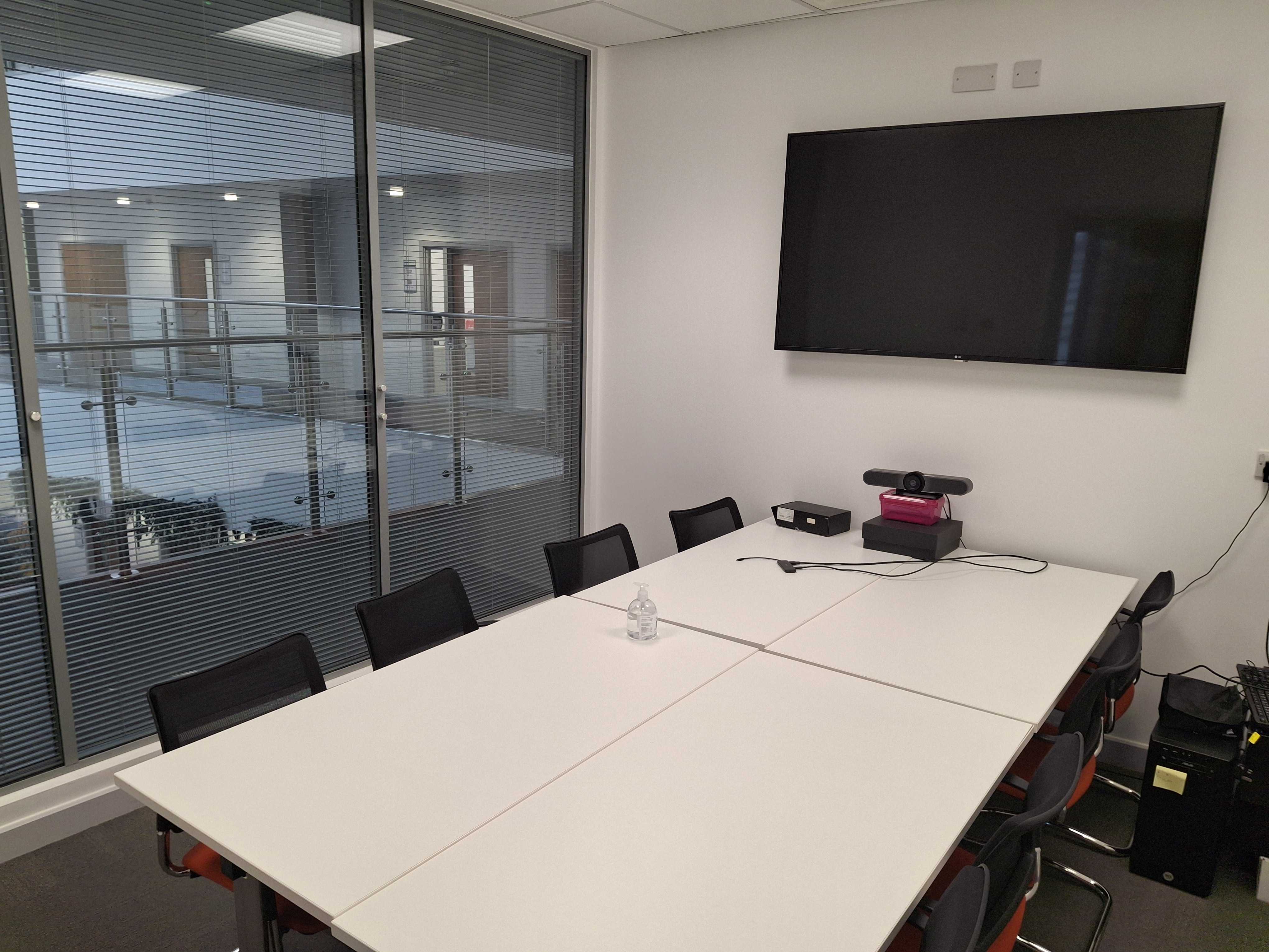 Our office meeting room with a large table, 8 chairs, and a large wall-mounted TV.