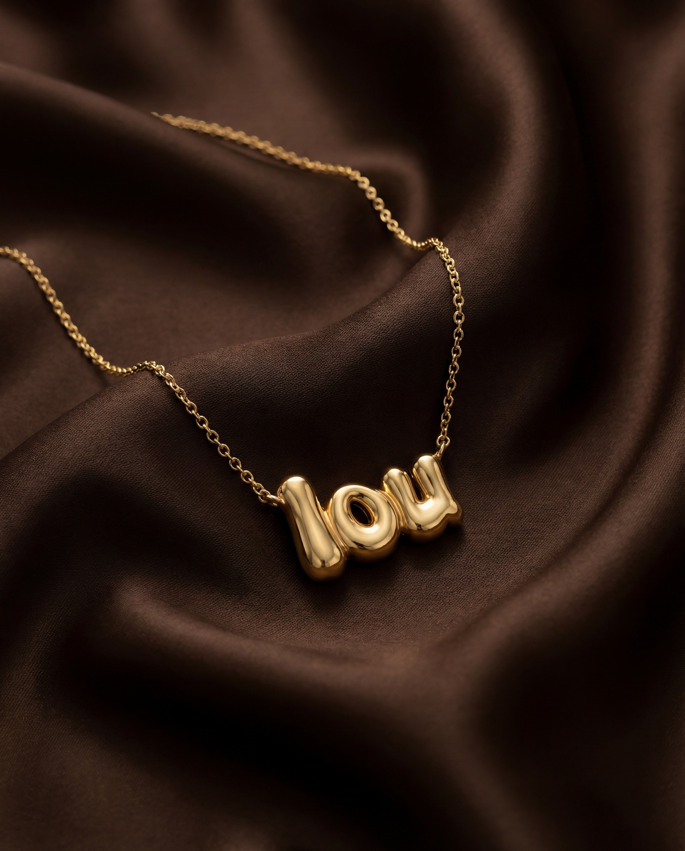 Vedder & Vedder — Gold Lou necklace resting on dark brown fabric.