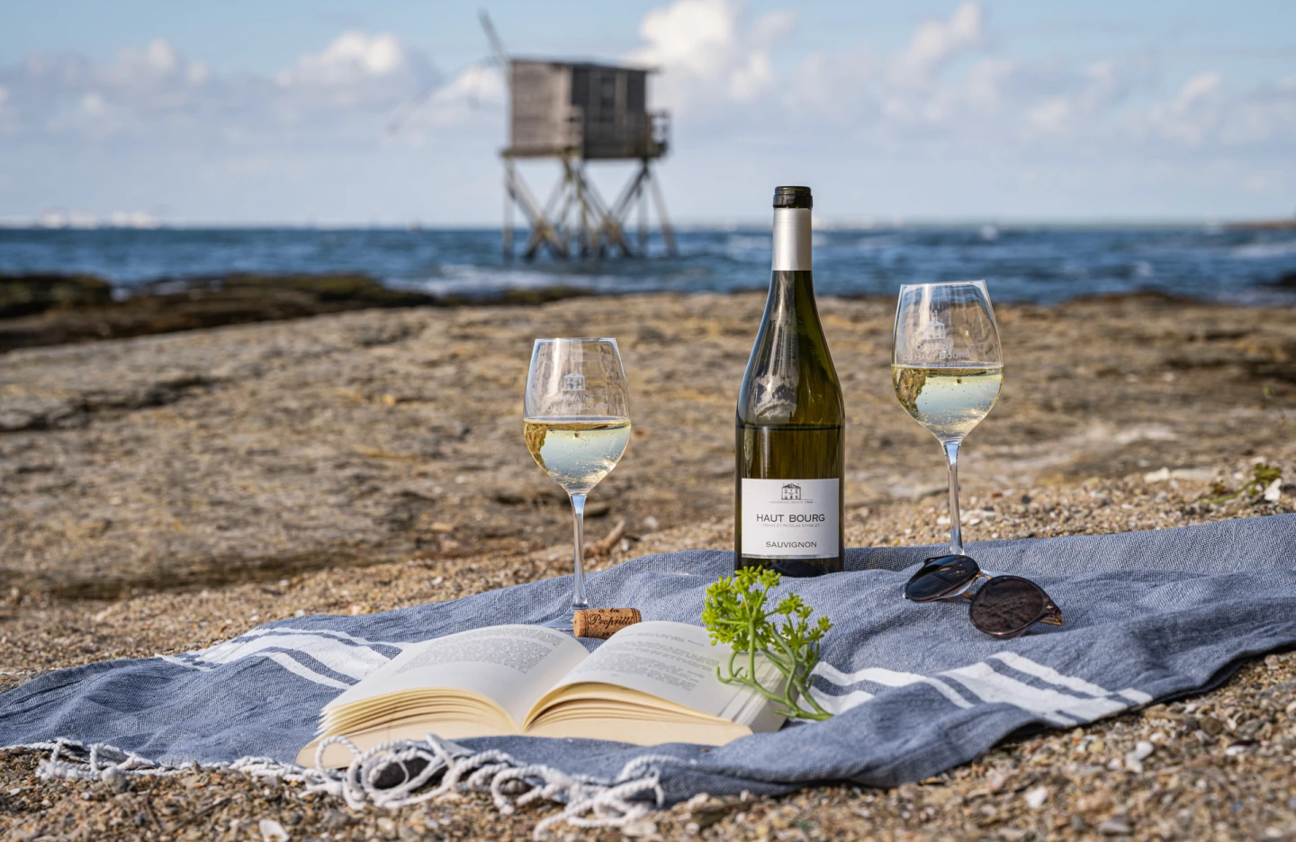 Bouteille de vin blanc et verres sur une serviette, face à l'océan