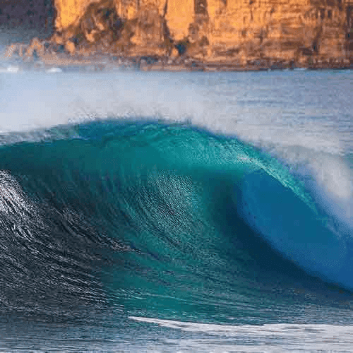 A large, turquoise wave crashing against shore – surfboard rental in central-coast