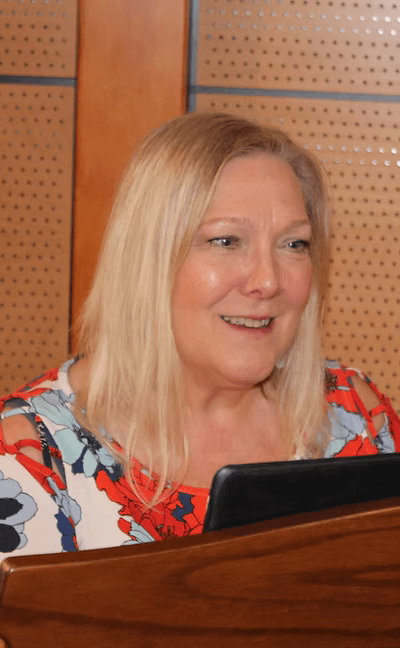 woman in gray coat singing on stage