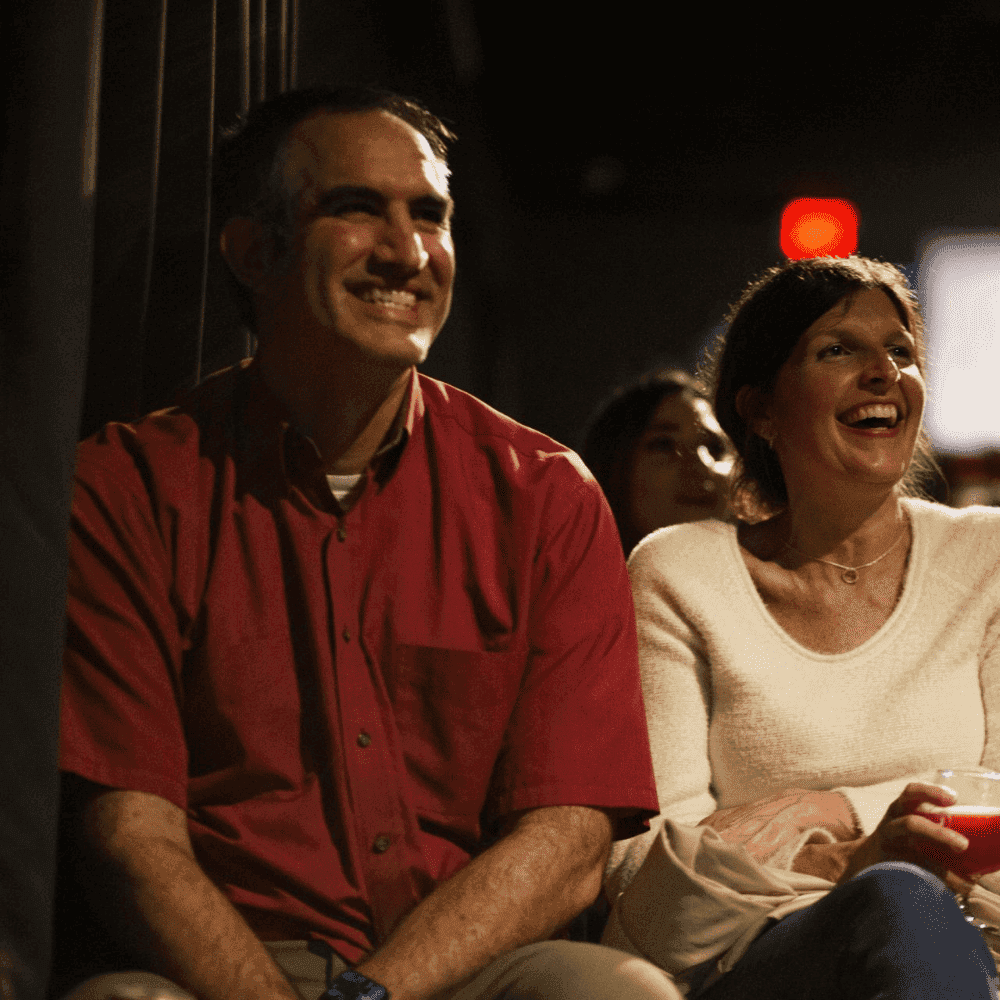 A husband and wife laughing at a joke during a St Pete Standup show