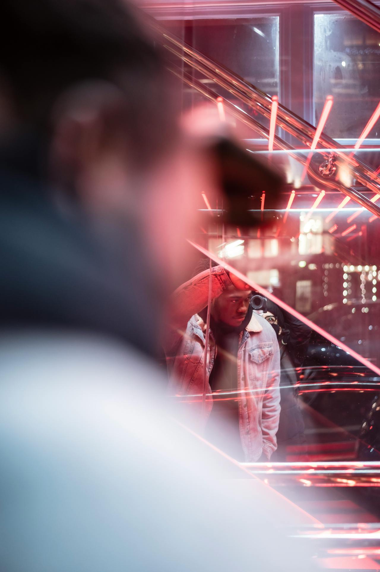 A smiling woman with her arms crossed, standing against a dark green background. She has long, dark hair.