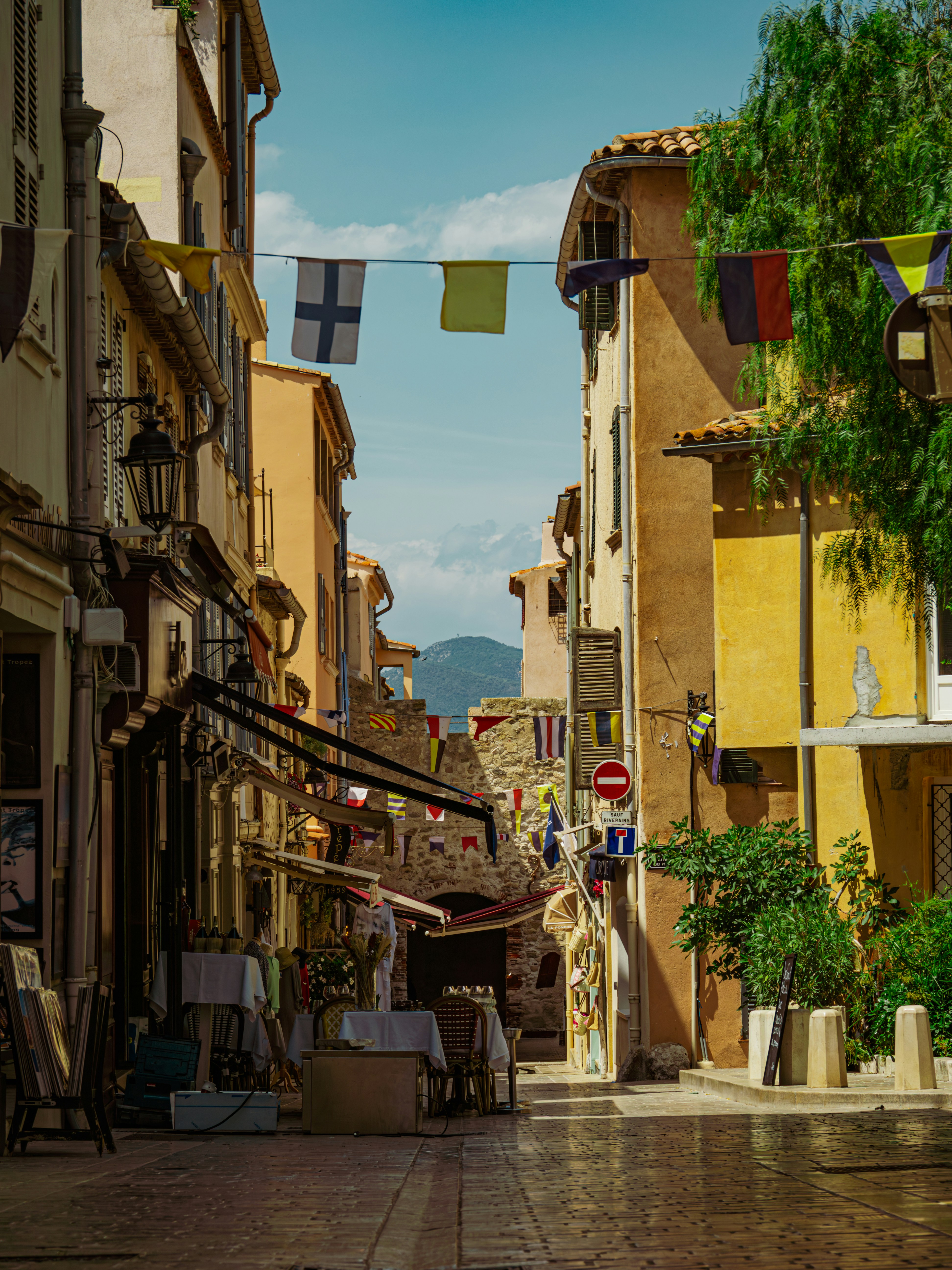 Narrow european street with colorful buildings and flags.