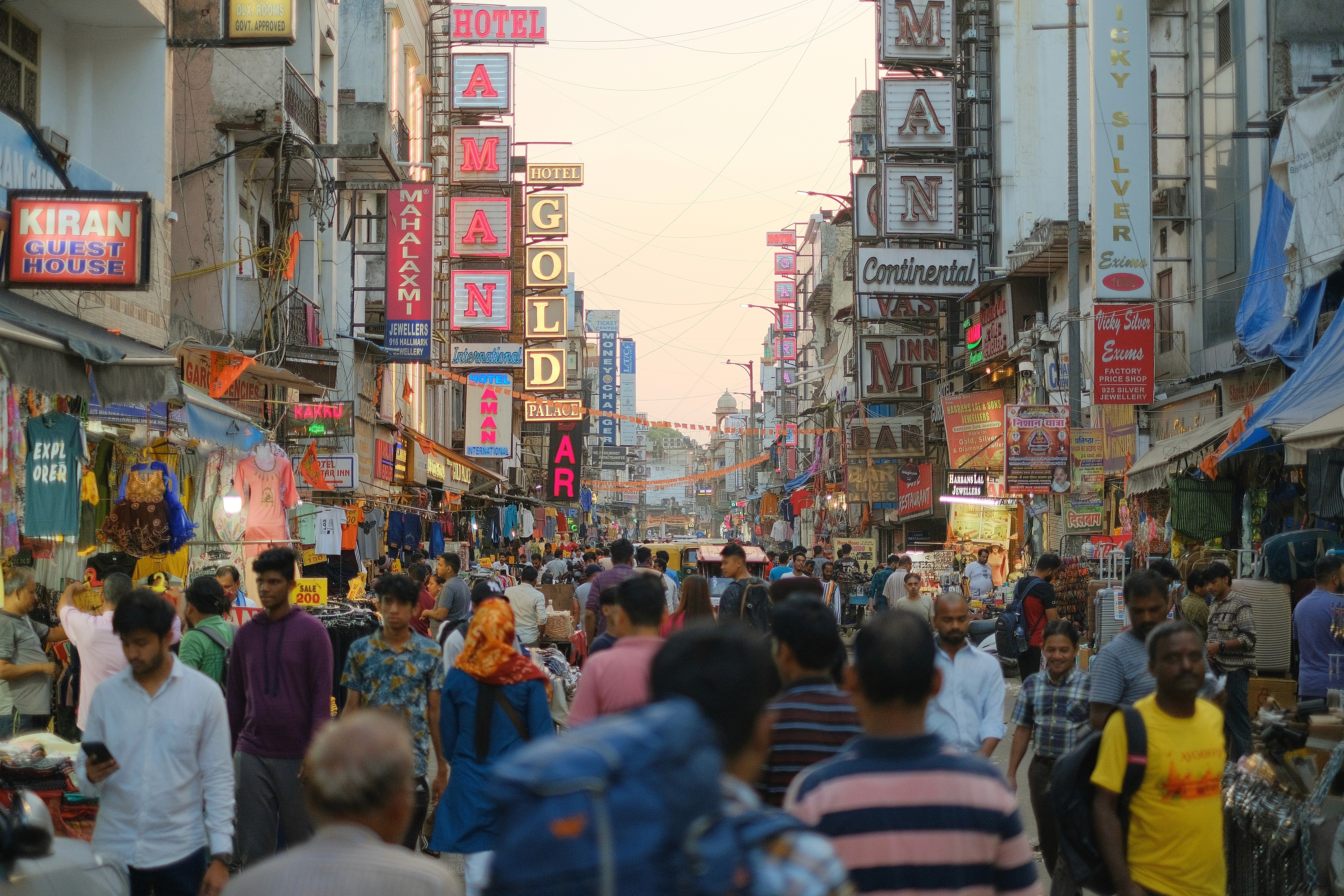 A backpacker walks down a crowded street in New Delhi with his back to the camera