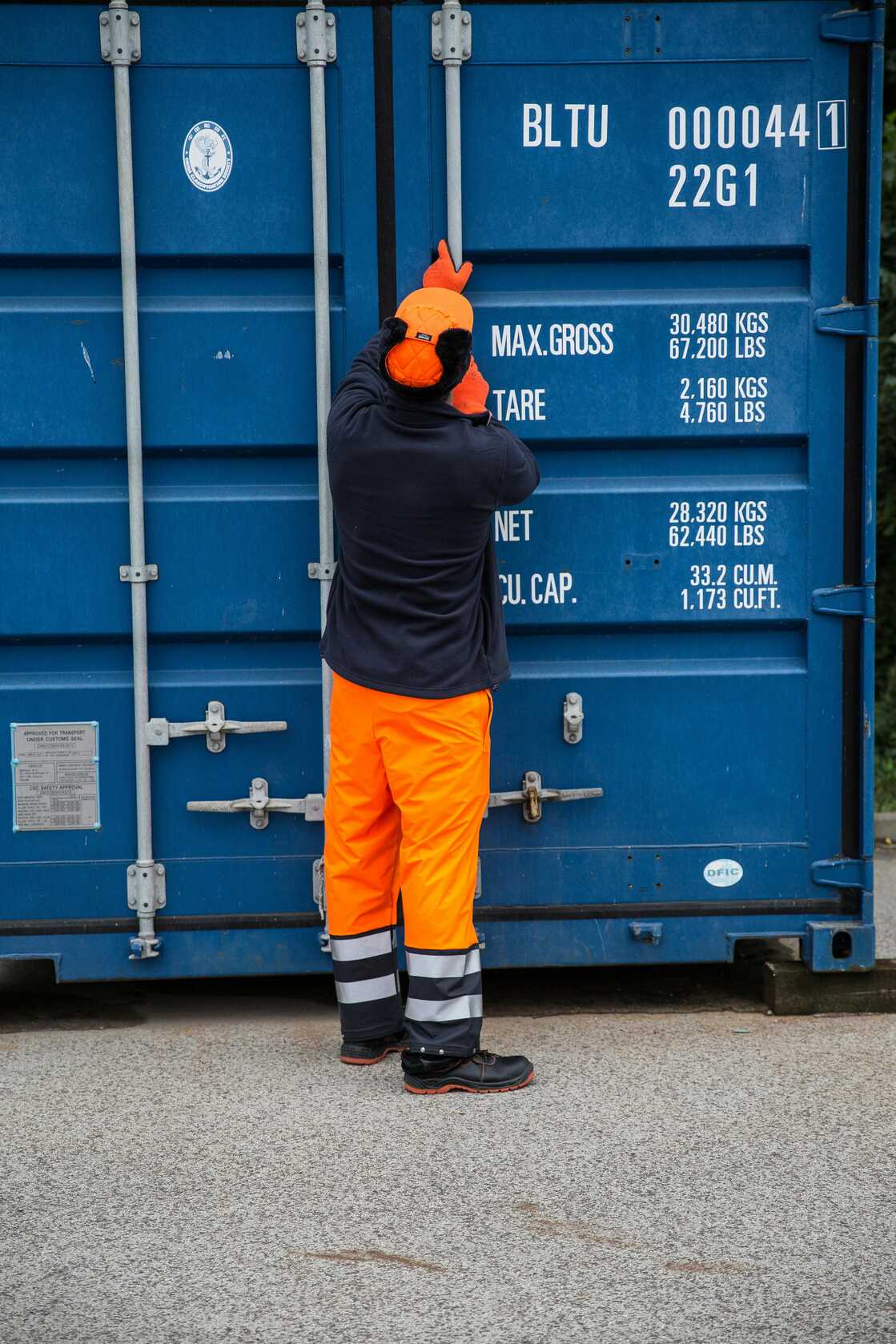 Worker in orange suit facing containers