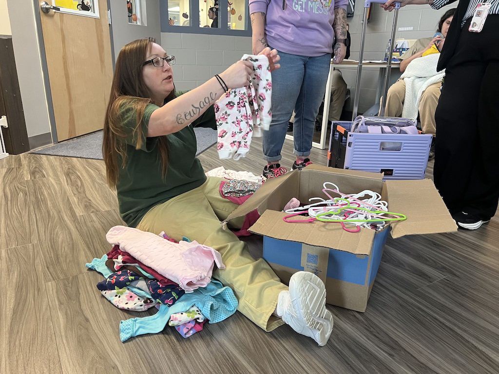 Tara Carroll, a nursery caregiver, sorts through and catalogs donated baby clothes.