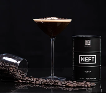 An espresso martini with a NEFT Vodka barrel and coffee beans against a dark background.