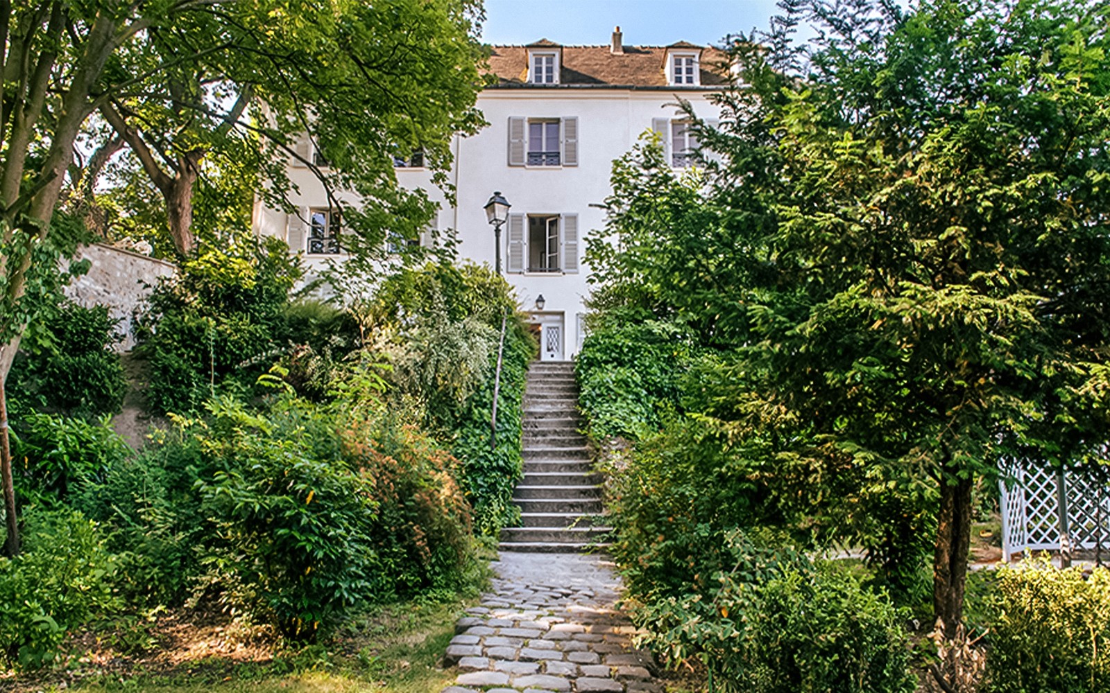 通往蒙马特尔博物馆入口的石道，被郁郁葱葱的绿植环绕。