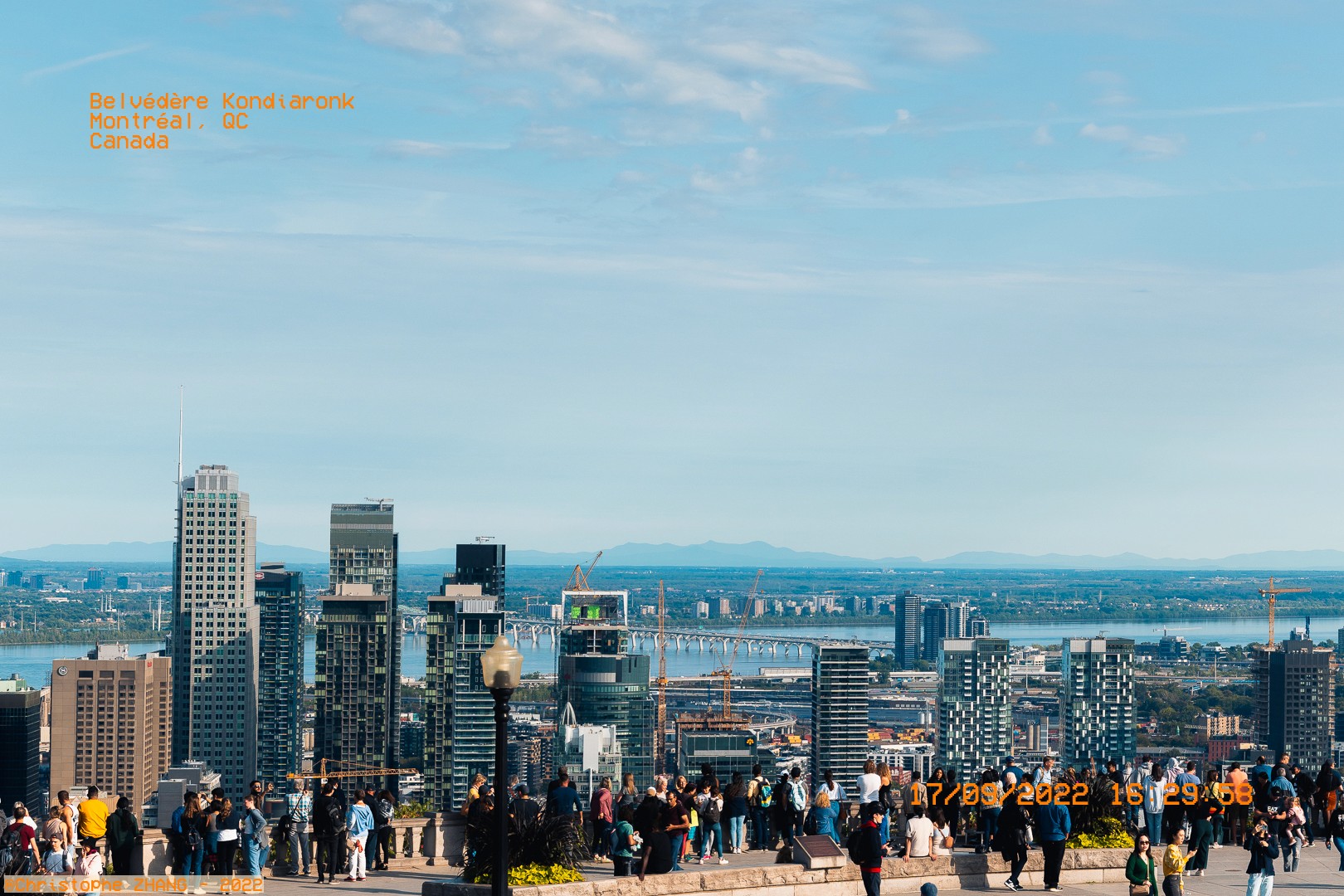 Vue panoramique du centre-ville de Montréal depuis le belvédère Kondiaronk, avec des visiteurs en premier plan.