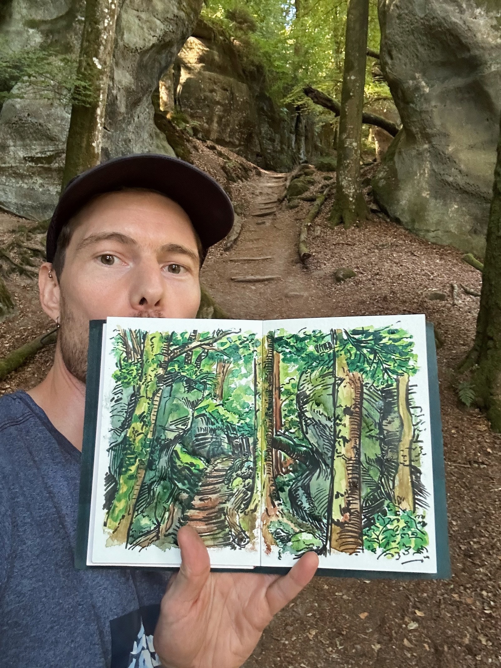 Matt holds up a sketch of the sandstone rocks and forest on Route 2 of the Mullerthal trail.