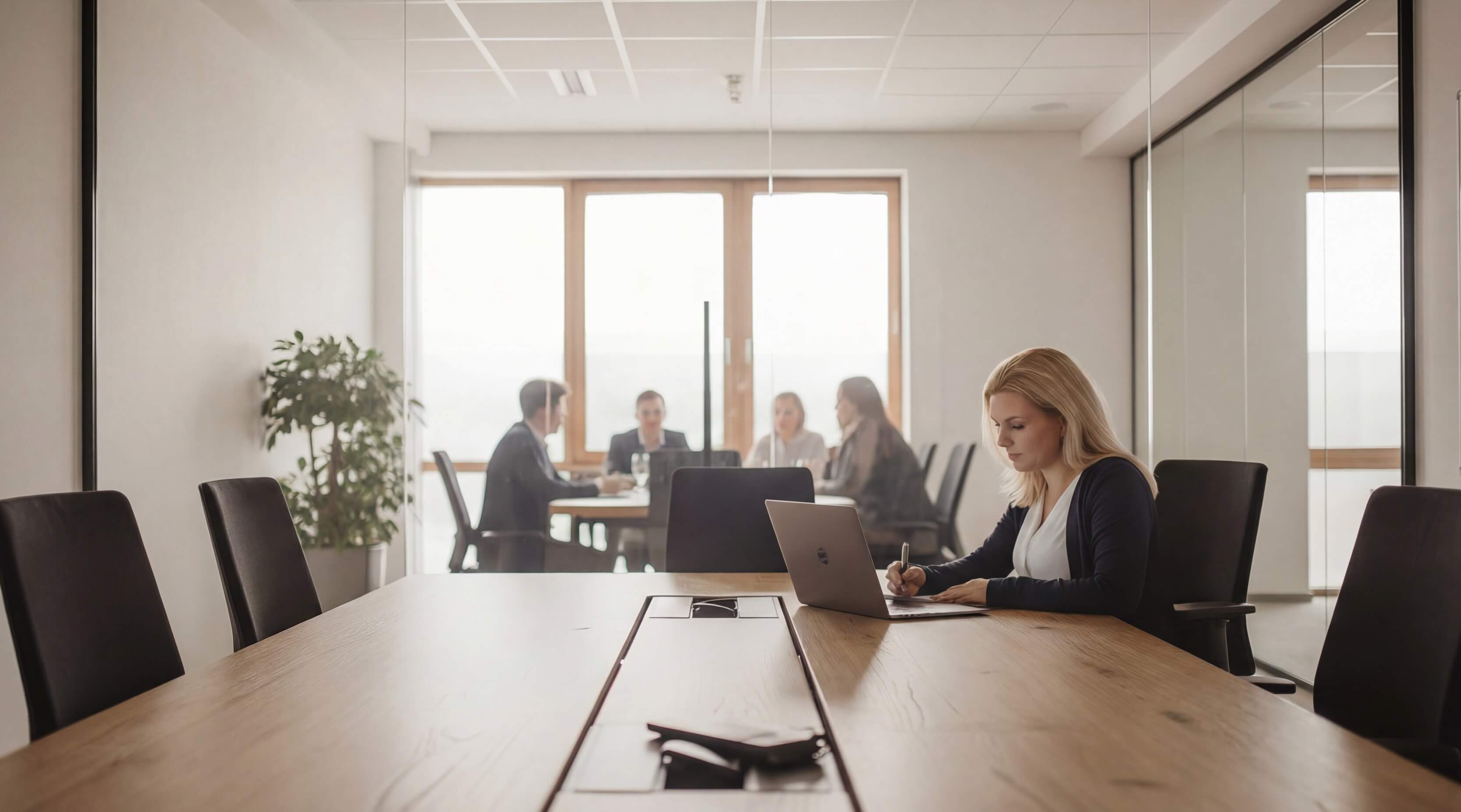 HR-Beraterin am Schreibtisch mit sichtbarem Teammeeting, die Expertise in Employer Branding und Recruiting demonstriert