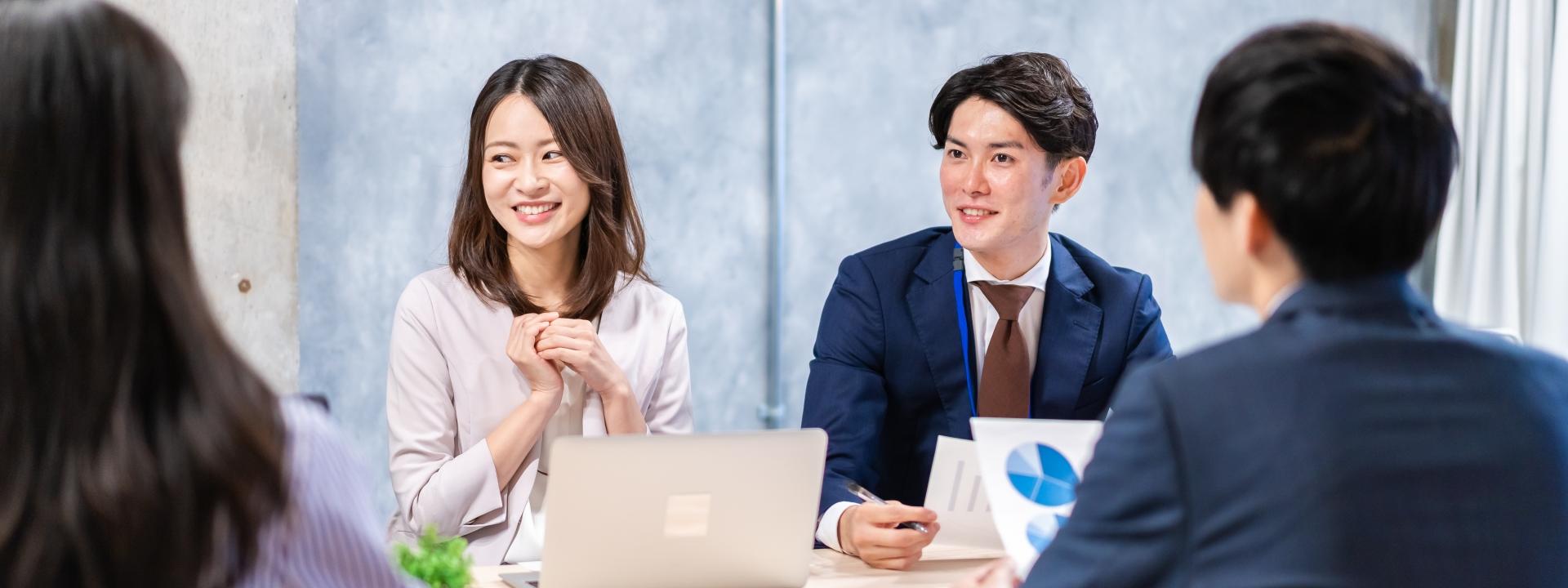 会議中に笑顔で話し合うビジネスパーソンたち
