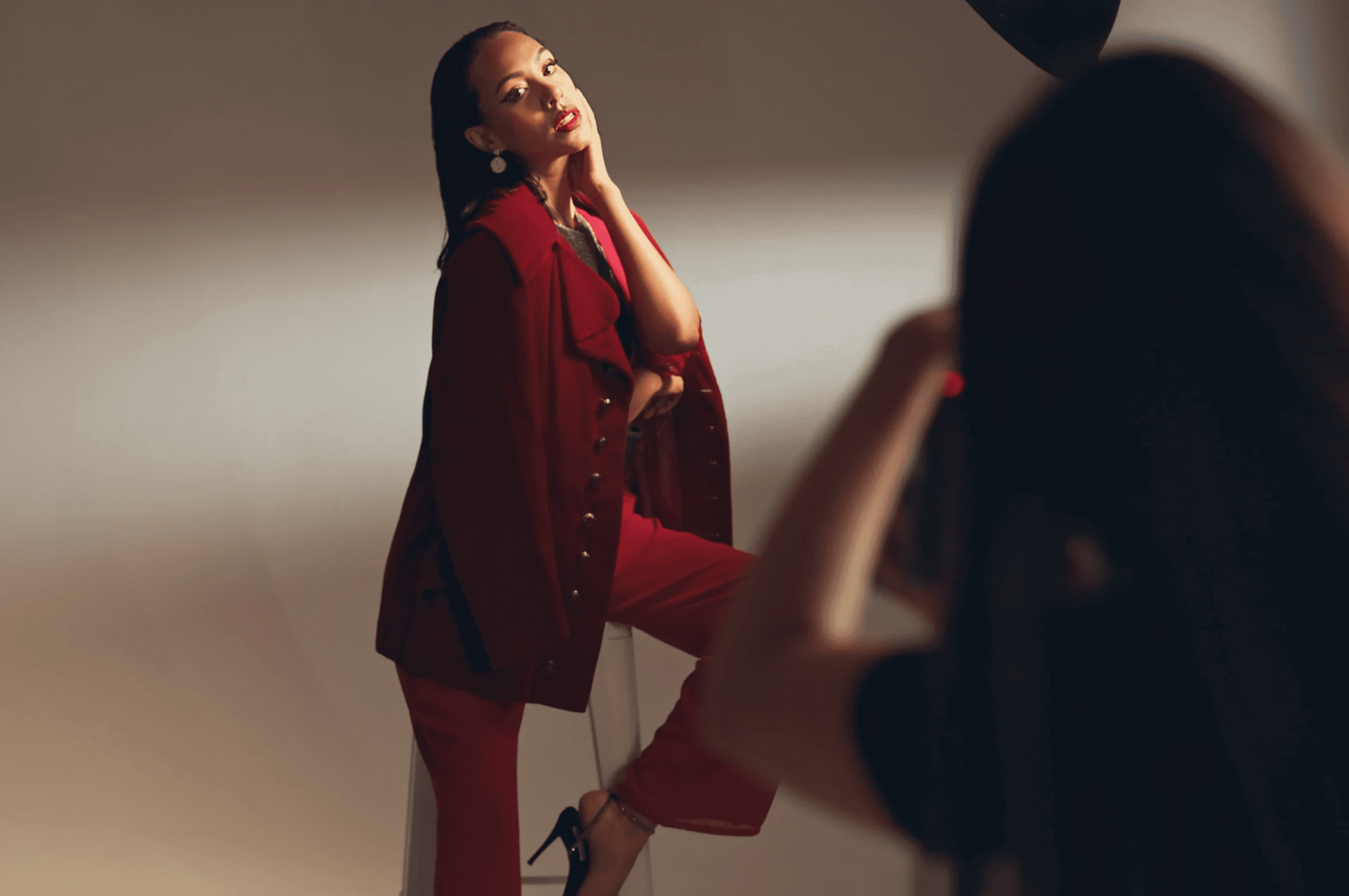 caramel skinned model wearing a fashionable red suit is getting her photo taken by a photographer